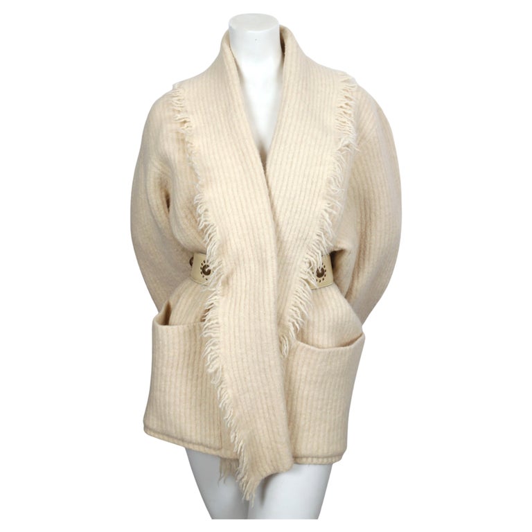 Cream wool cardigan sweater with shawl neckline, fringed trim and patch pockets from Azzedine Alaia dating to 1985. Labeled a size S although this will fit a many sizes due to oversized cut. Approximate measurements: shoulder 18