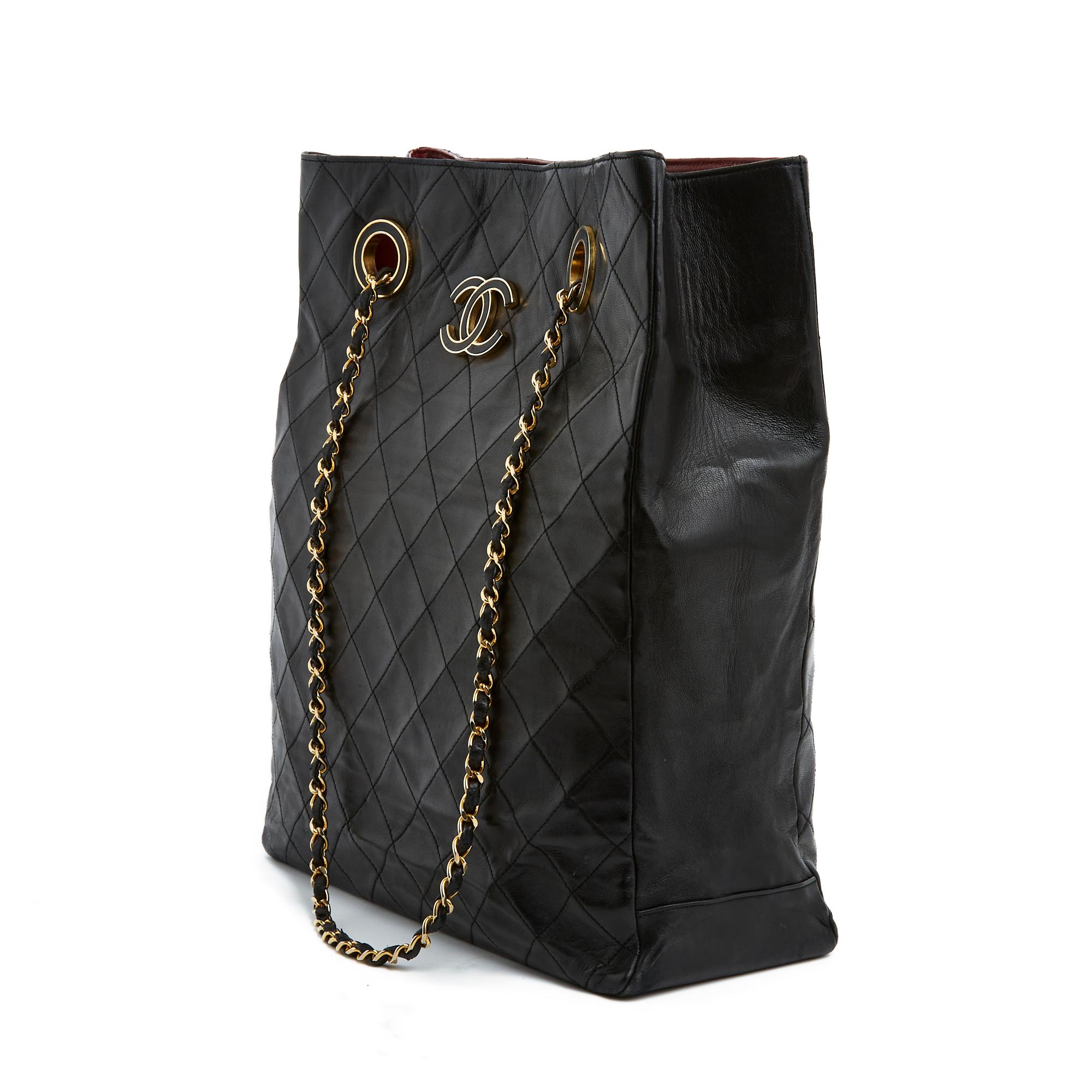 Sac Chanel Haute Couture circa 1985 en cuir matelassé noir, grand logo CC recouvert de cuir noir sur un côté, intérieur en cuir bordeaux avec une grande poche zippée et une autre poche plaquée, fermeture du sac par 2 boutons pression, très longue