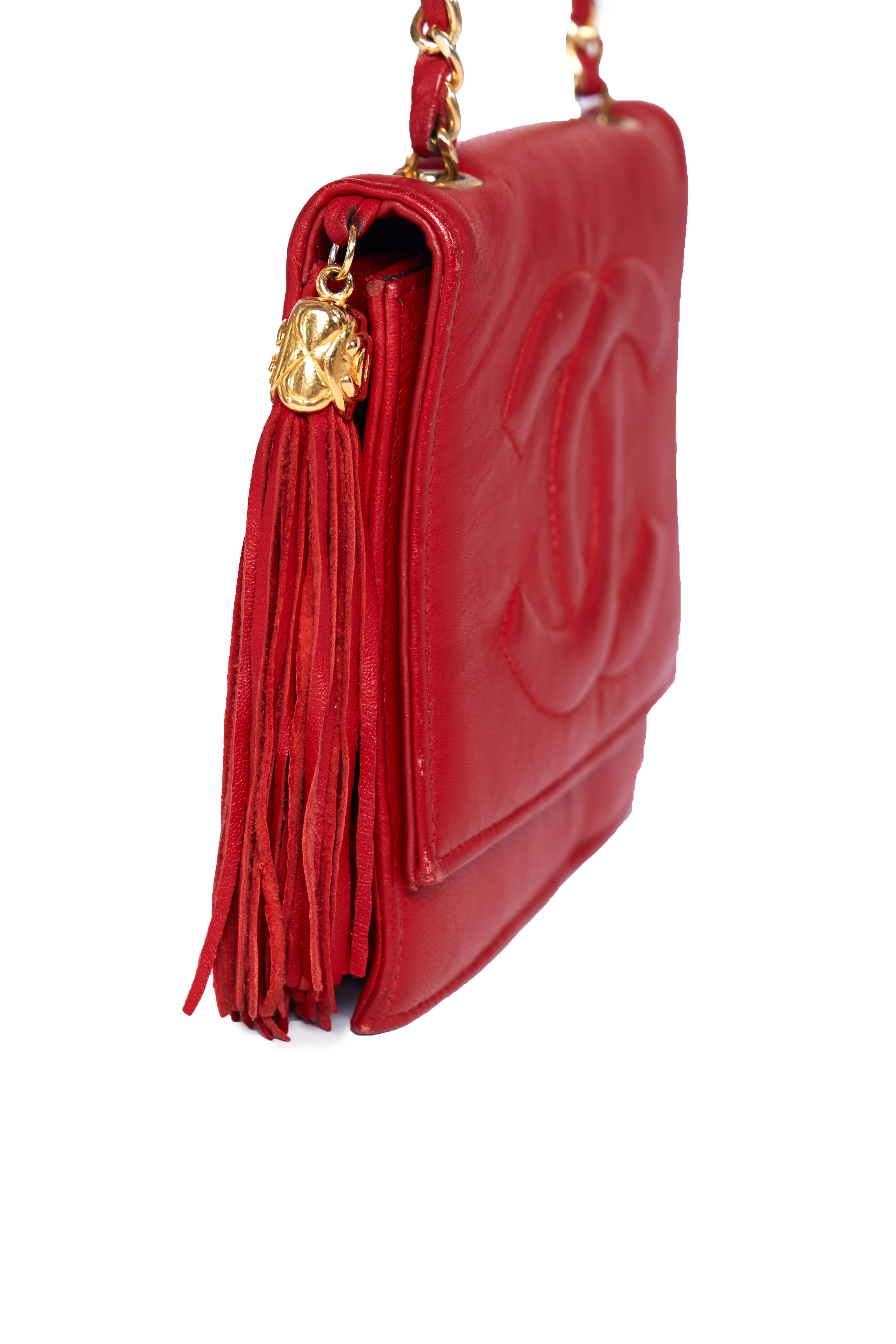  Chanel Vintage Mini Tassel Flap Bag 1985
Trésor rare des années 80, ce rabat miniature Chanel est taillé dans une peau d'agneau rouge vif et doté des accessoires plaqués or 24 carats emblématiques de la maison. Le logo CC surpiqué surdimensionné