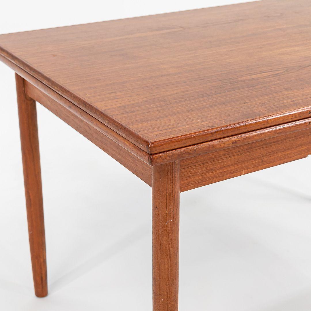 This is a Teak Extension Dining Table attributed to Ansager Mobler, produced in Denmark in 1985. The table features two leaves that extend the piece by 18 inches on each side, and has four round slightly tapered legs in solid teak. It is a well-made