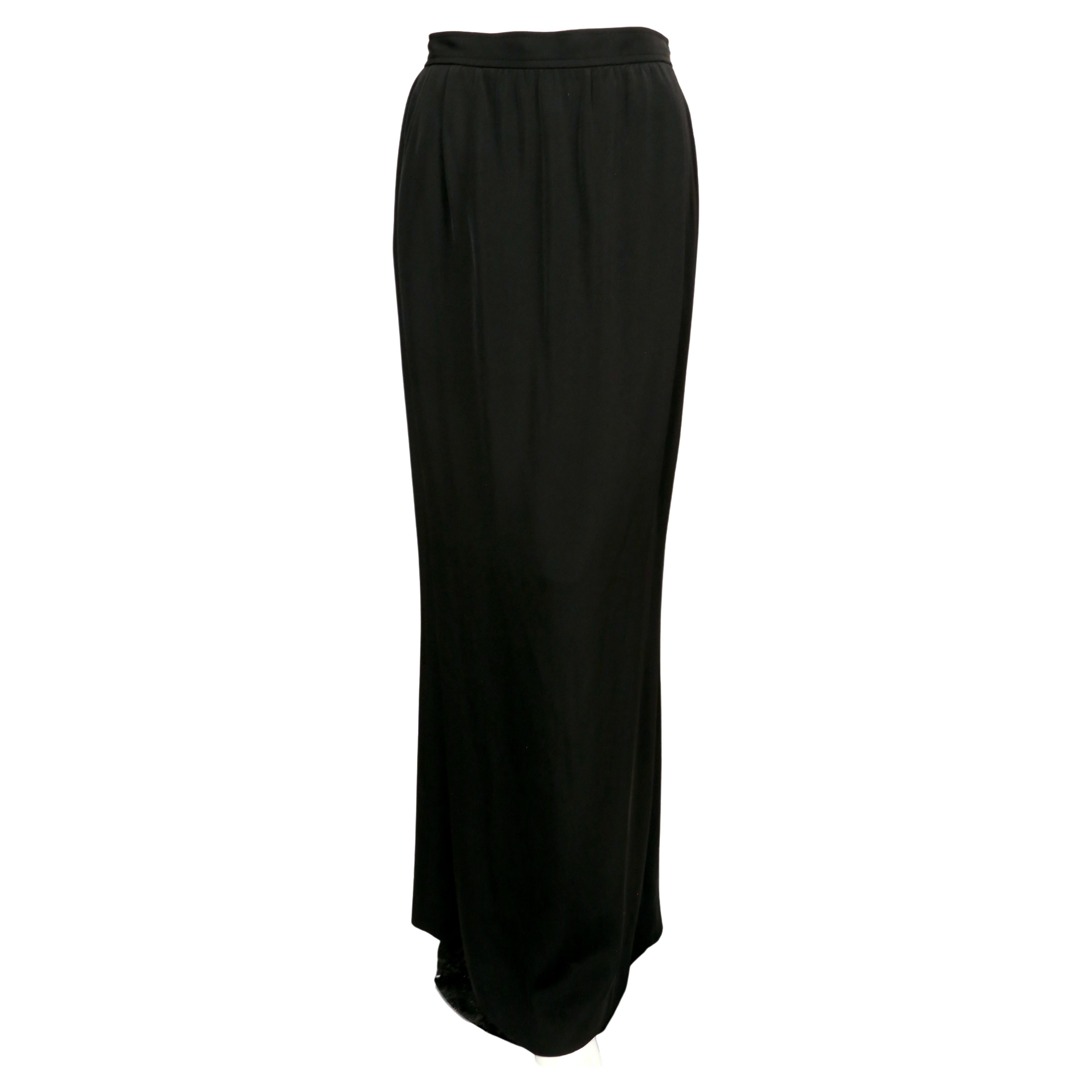 Jupe Rive Gauche d'Yves Saint Laurent, collection automne 1985. Conçue en acétate et viscose noirs, la jupe est coupée dans une silhouette étroite et longue comme le sol. Une rangée de gros boutons en strass court sur toute la longueur de la jupe,