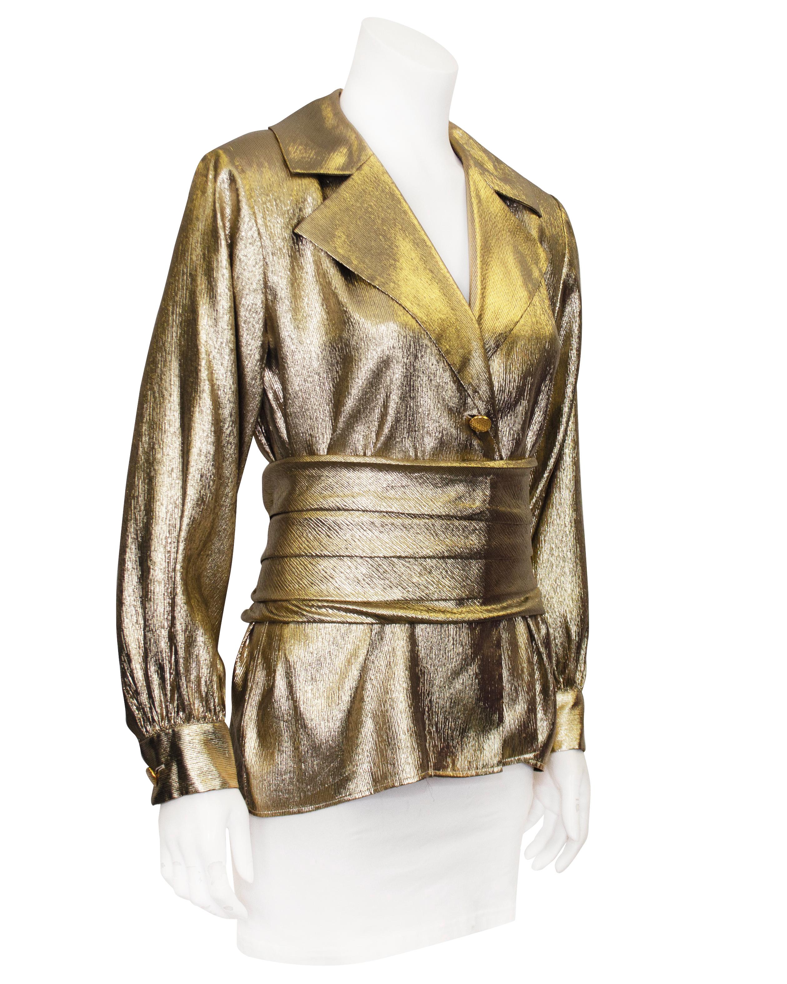 Worn on the runway for the 1985 Fall Ready to Wear collection, this gold evening blouse with matching cummerbund is meant to be worn tucked in to evening pants or a skirt. The shirt is made of shimmery gold lurex fabric and has a notched lapel with