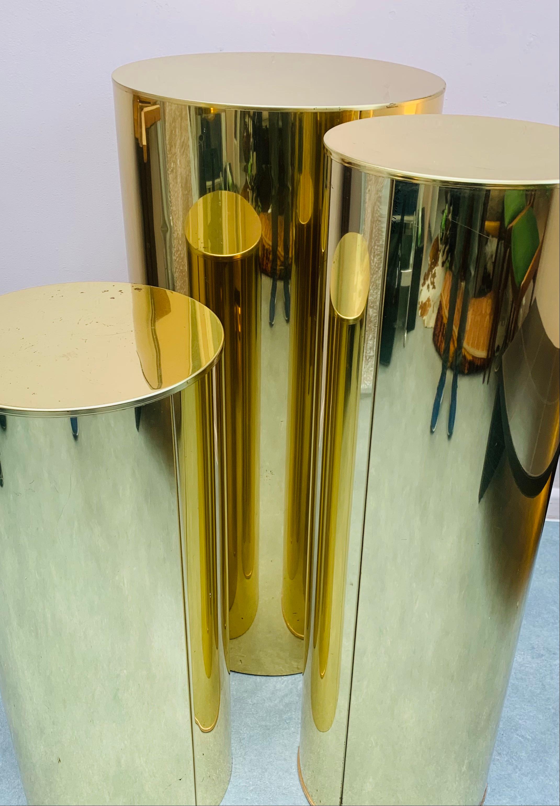 An interesting set of three polished chromed-brass cylindrical display pedestals or columns of varying height and diameter designed by Curtis Jere for Artisan House. One pedestal is signed 