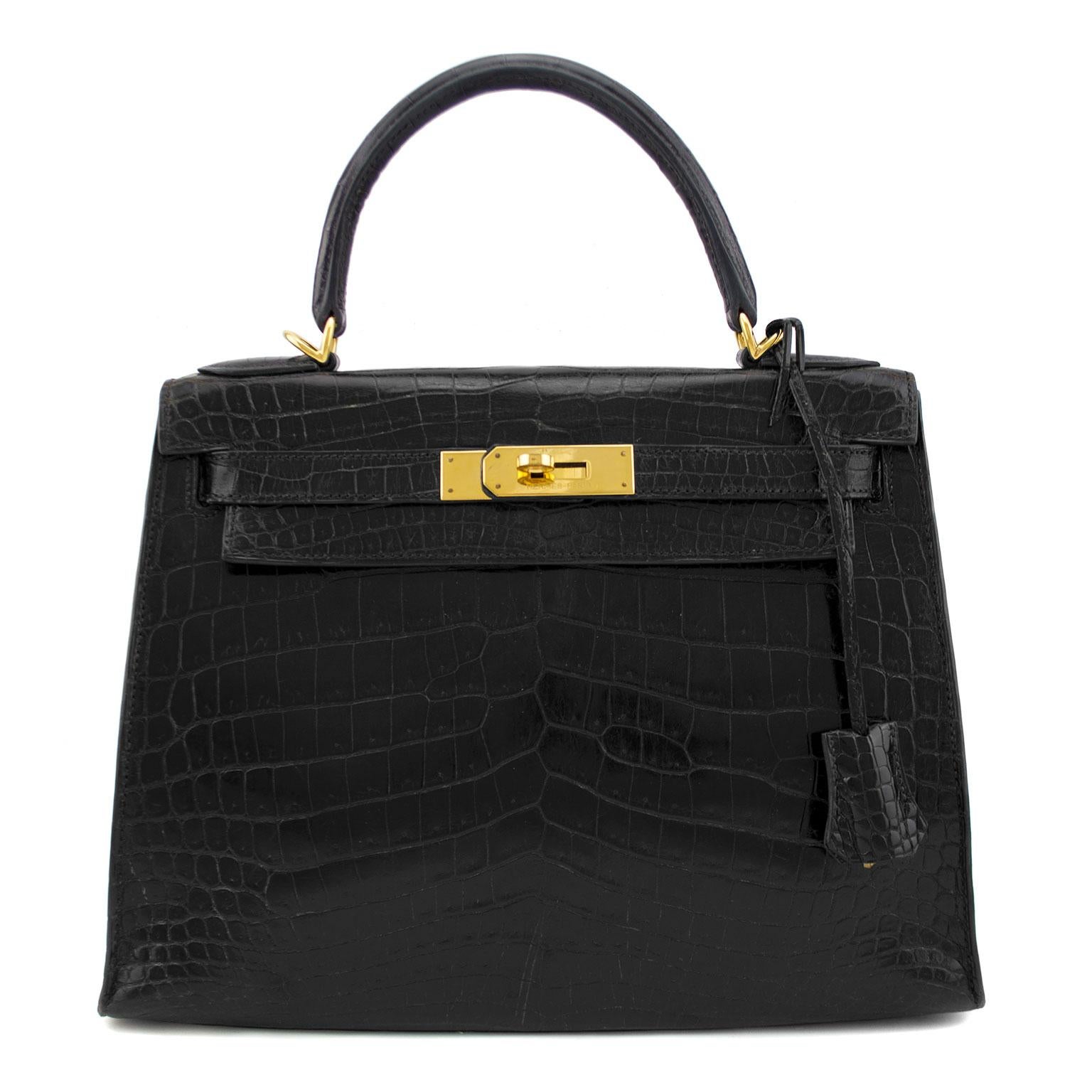 1987 Noir Niloticus crocodile Hermès Kelly Sellier 28 with gold-plated hardware, optional shoulder strap, single flat top handle, tonal leather interior, three pockets at interior walls; one with zip closure and flap with turn-lock closure at front.