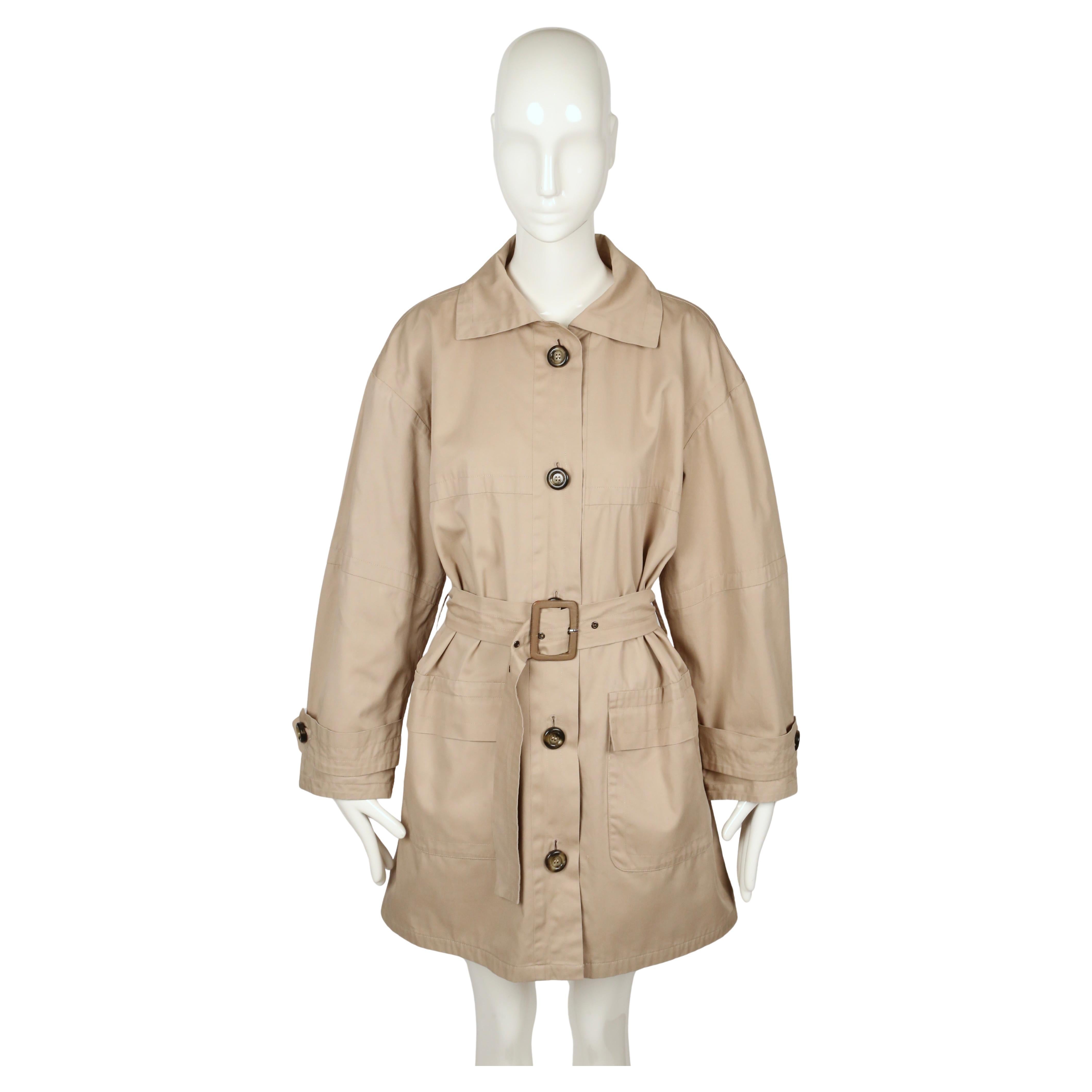 Un abrigo clásico de algodón beige Yves Saint Laurent Rive Gauche de 1987, cortado en una silueta fácil y oversize que refleja la sastrería relajada pero refinada de la década. El abrigo tiene cuello de pico, cierre de botones de un solo pecho con