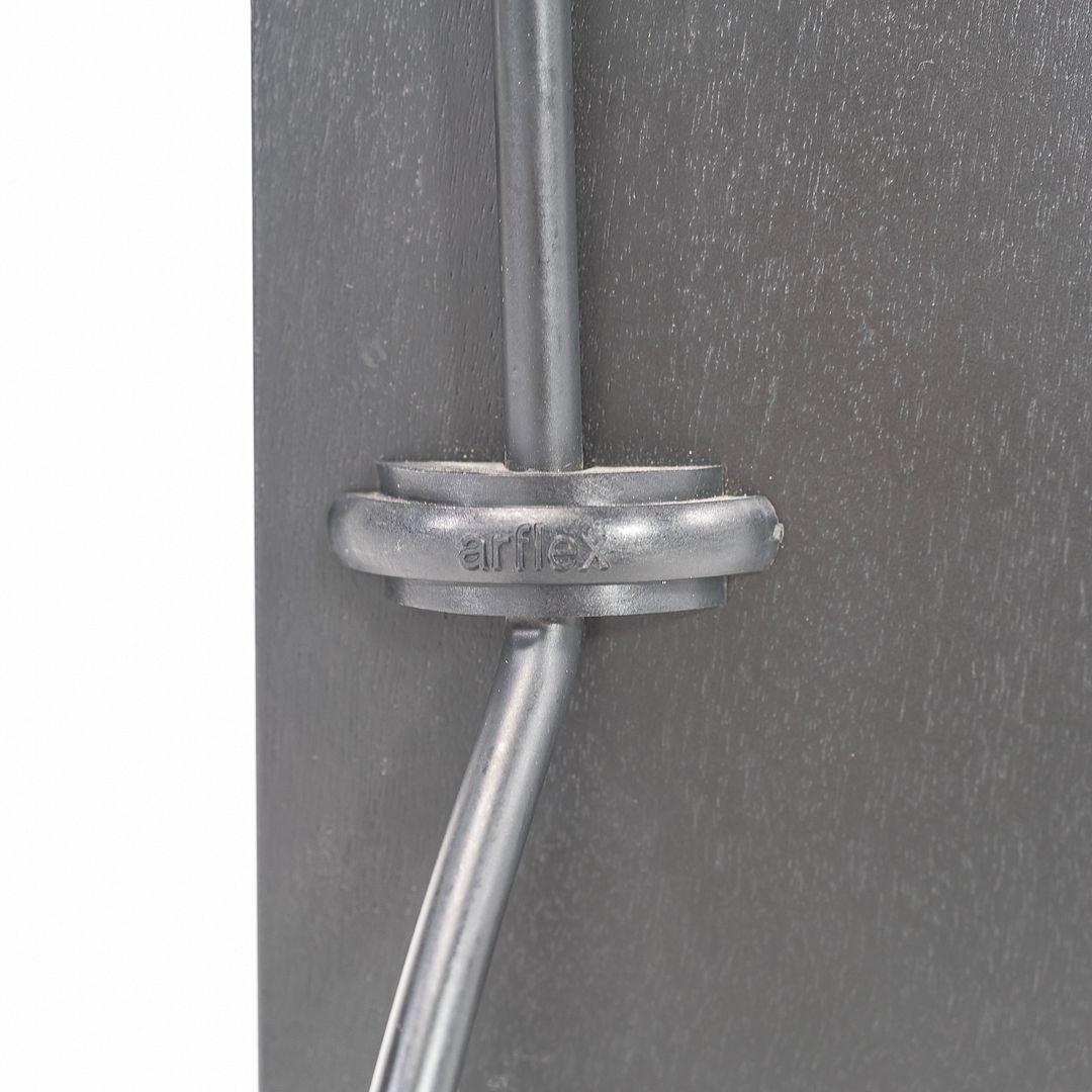 Se trata de una silla auxiliar Elasta de madera curvada ebonizada y acero, diseñada por Jesse Martin para Arflex Italia en 1988. Tiene una sólida silueta Po-Mo, indudablemente italiana, y ofrece un amplio apoyo gracias a su asiento y respaldo de