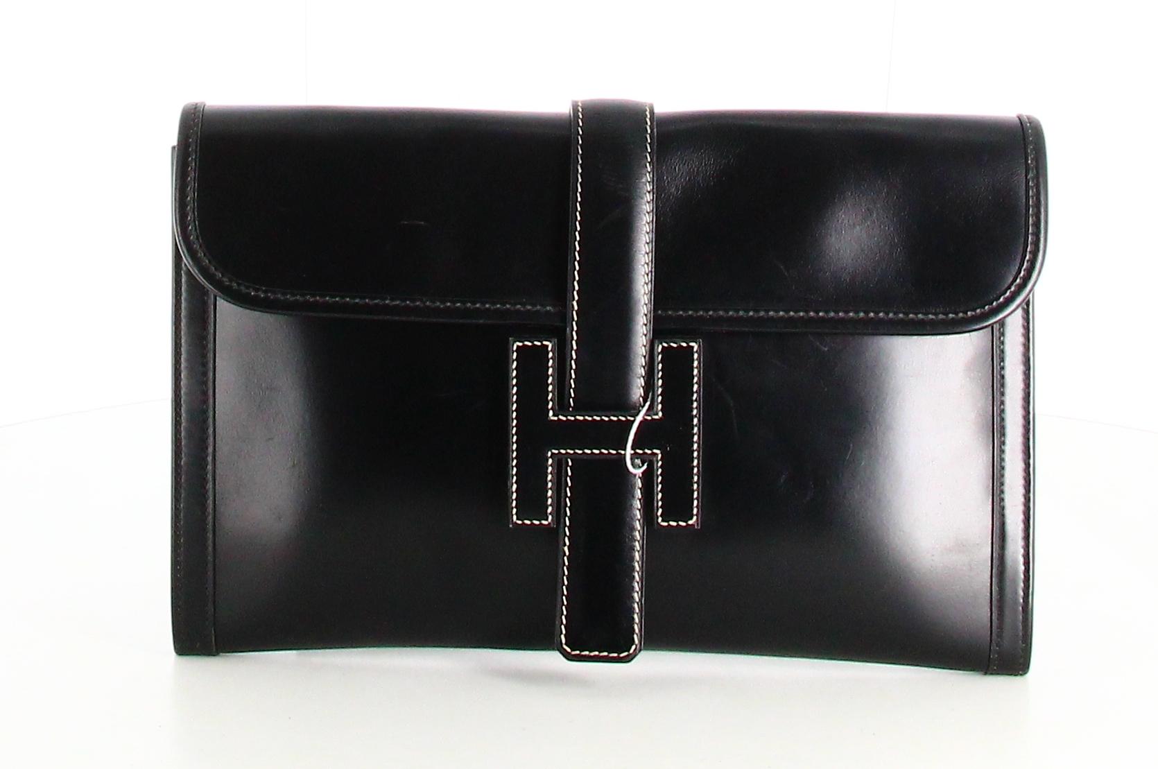 1988 Hermès Jige PM Clutch Bag Black Leather

- Good condition. Slight traces of wear over time. 
- Hermès Clutch bag 
- Black leather 
- Clasp: black leather hanse with H logo 
- Interior: Beige canvas