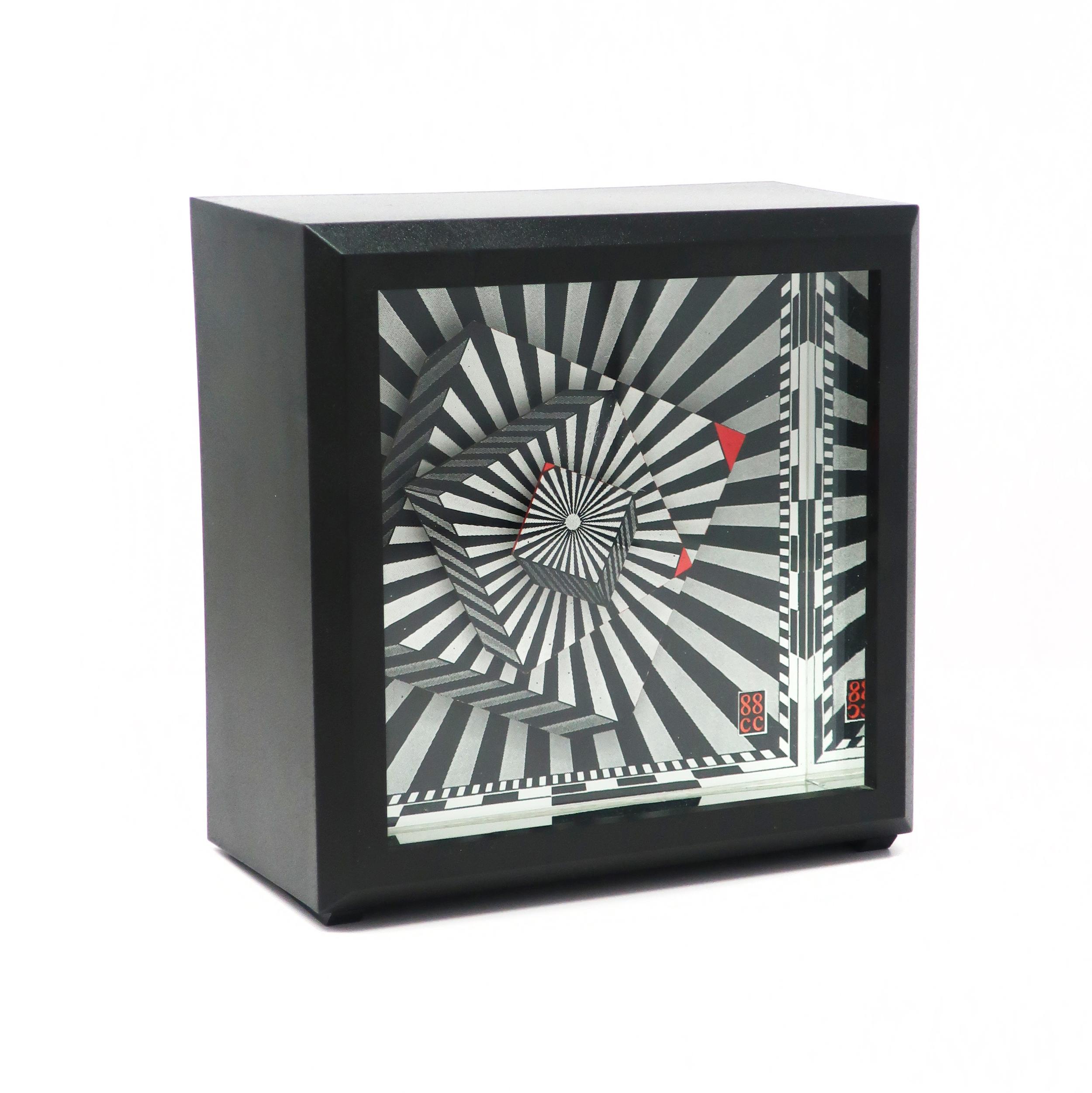 A rare 1988 desk clock designed by Douglas Chalk for clever clocks. A square plastic case, mesmerizing black and white psychedelic hands, and orange triangles at the tip of each hand. 

In very good vintage condition and in original