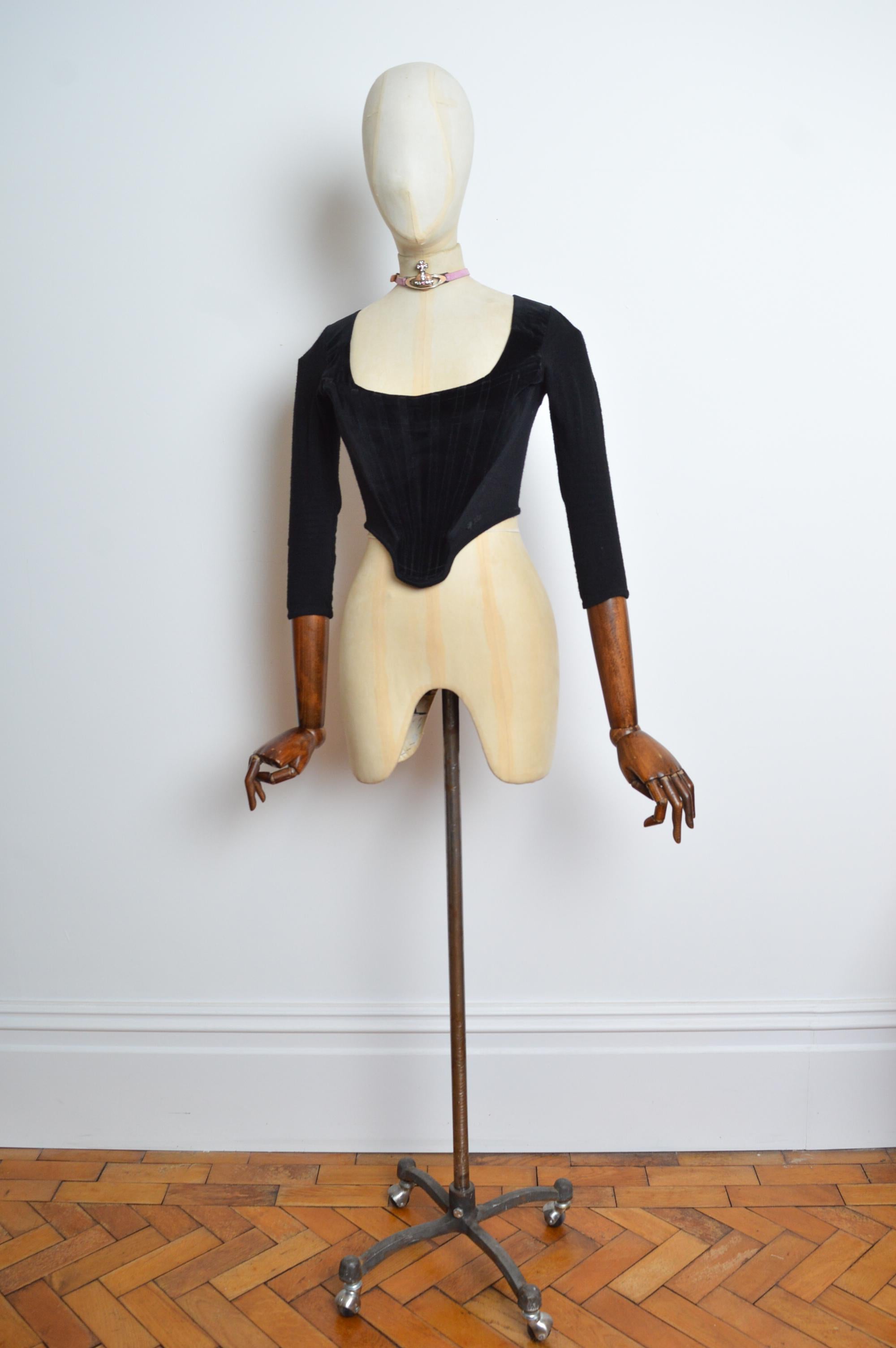 A 1988 Vivienne Westwood boned, velvet & jersey corset, with 3/4 length sleeves and zip fasten closure. 
Size; Recommended UK 4 - 6. 
Measurements are provided in inches (‘’)
Pit to Pit; 15.5’’
Pit to Cuff; 14’’
Top of Shoulder to Hem; 17’’
Waist;