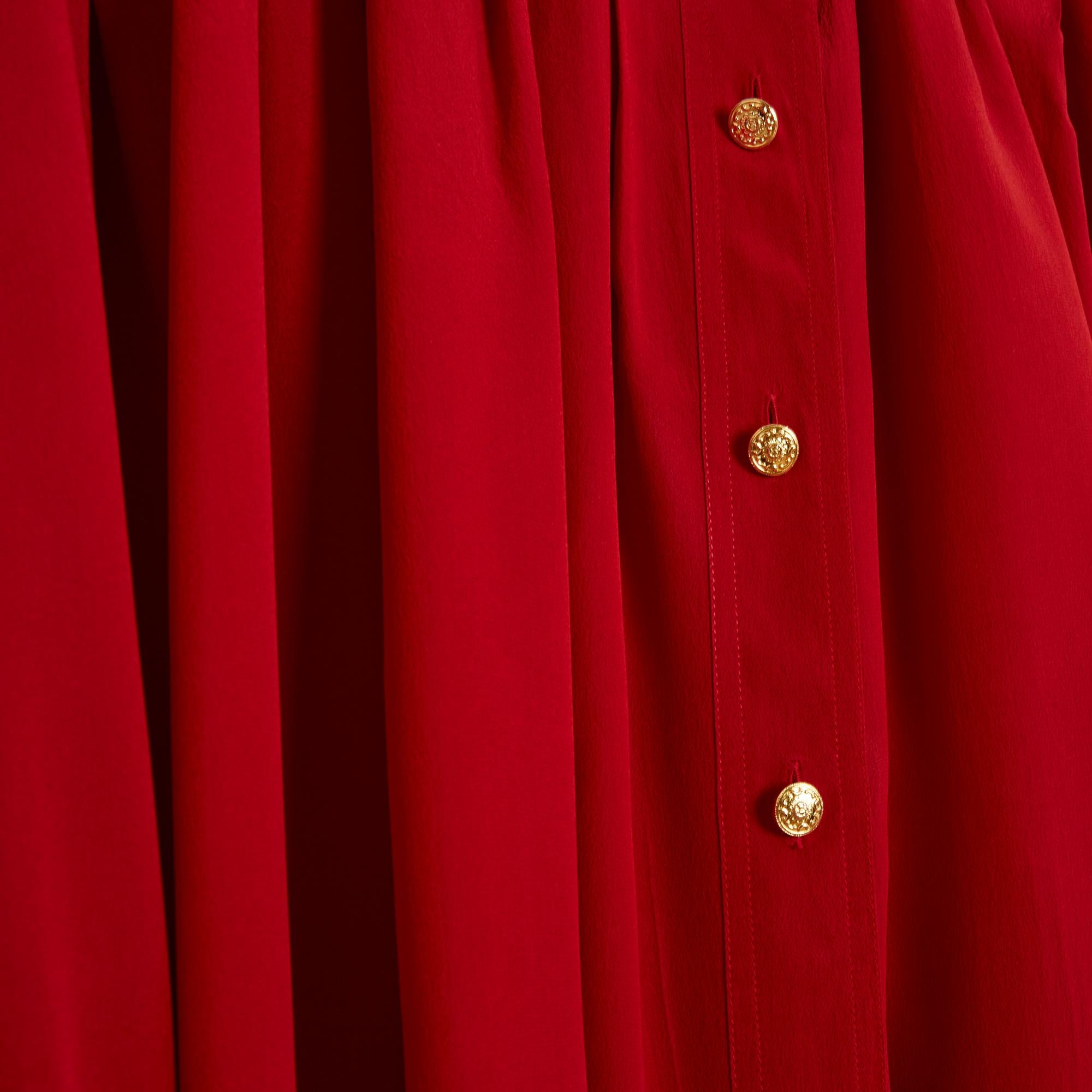 Chanel Top Bluse circa 1989 aus rotem Seidenkrepp, vorne und hinten von den Schultern her plissiert, Hemdkragen geschlossen mit 6 CC-Logo-Knöpfen aus goldenem Metall, lange Ärmel geschlossen mit passenden Manschettenknöpfen. Größe 40FR ungefähr