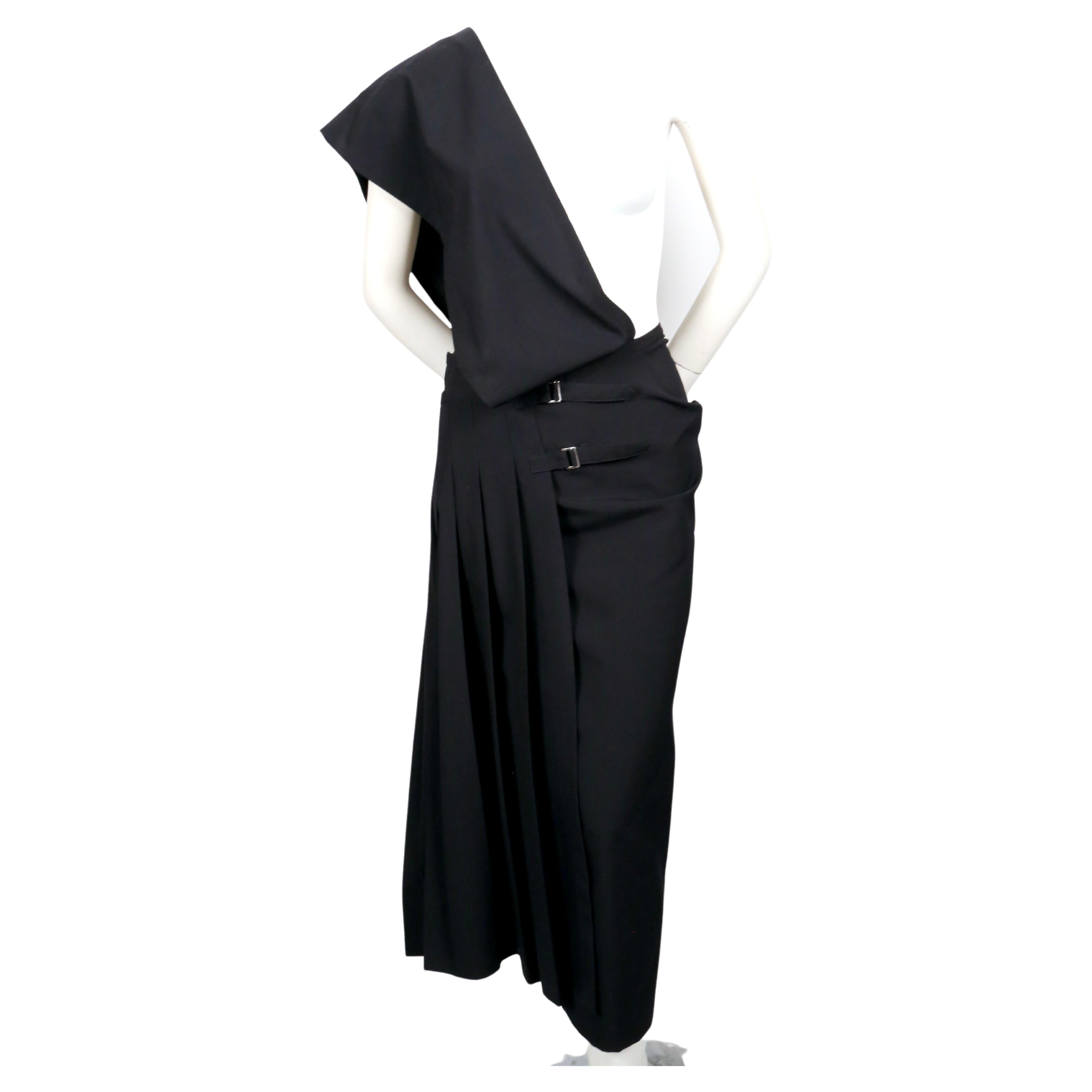 Black, asymmetrical one shoulder dress with wrap around pleated skirt designed by Rei Kawakubo for Comme Des Garcons dating to 1989. Size 'M'. Approximate measurement at interior of waist 28