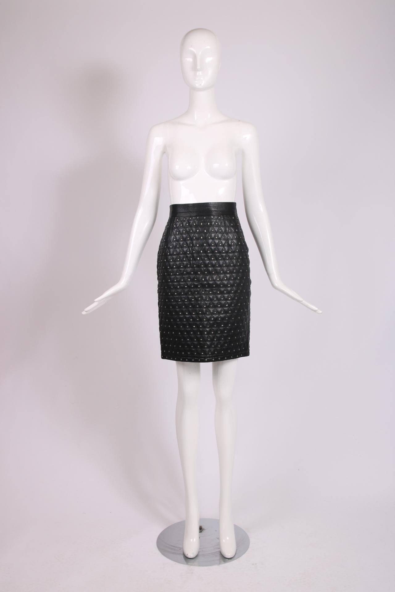 1989 F/W Gianni Versace black leather skirt quilted in a pattern of repeating adjacent, stacked triangles and embellished with textured silvertone studs. Skirt features an overstitched waistband, a 4 1/2
