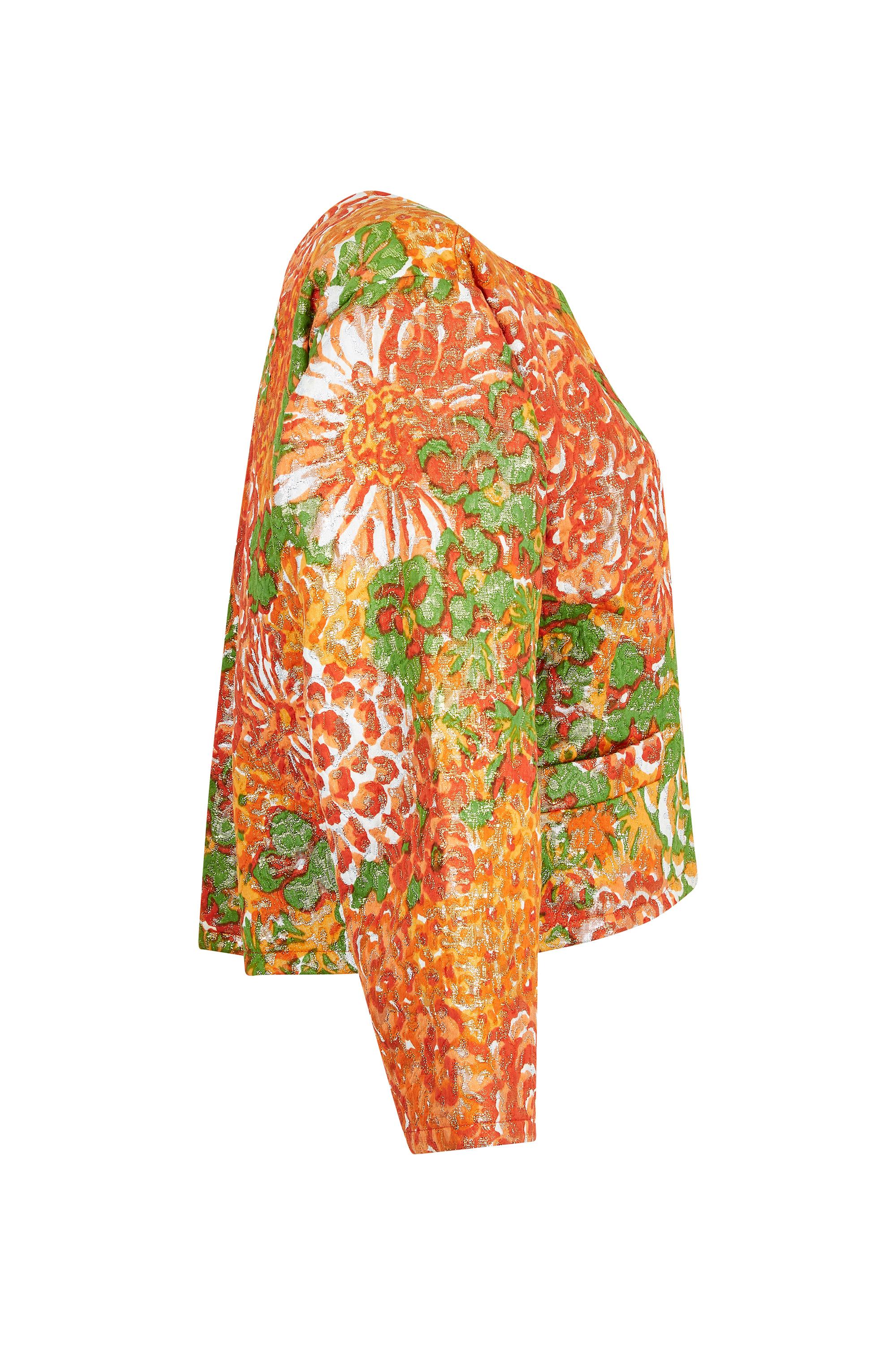 This fabulous 1989 documented lamé floral brocade jacket in tangerine, gold and green is by Yves Saint Laurent, is from a celebrated collection, and is in excellent vintage condition. Designed to be worn open, there are no fastenings and the the