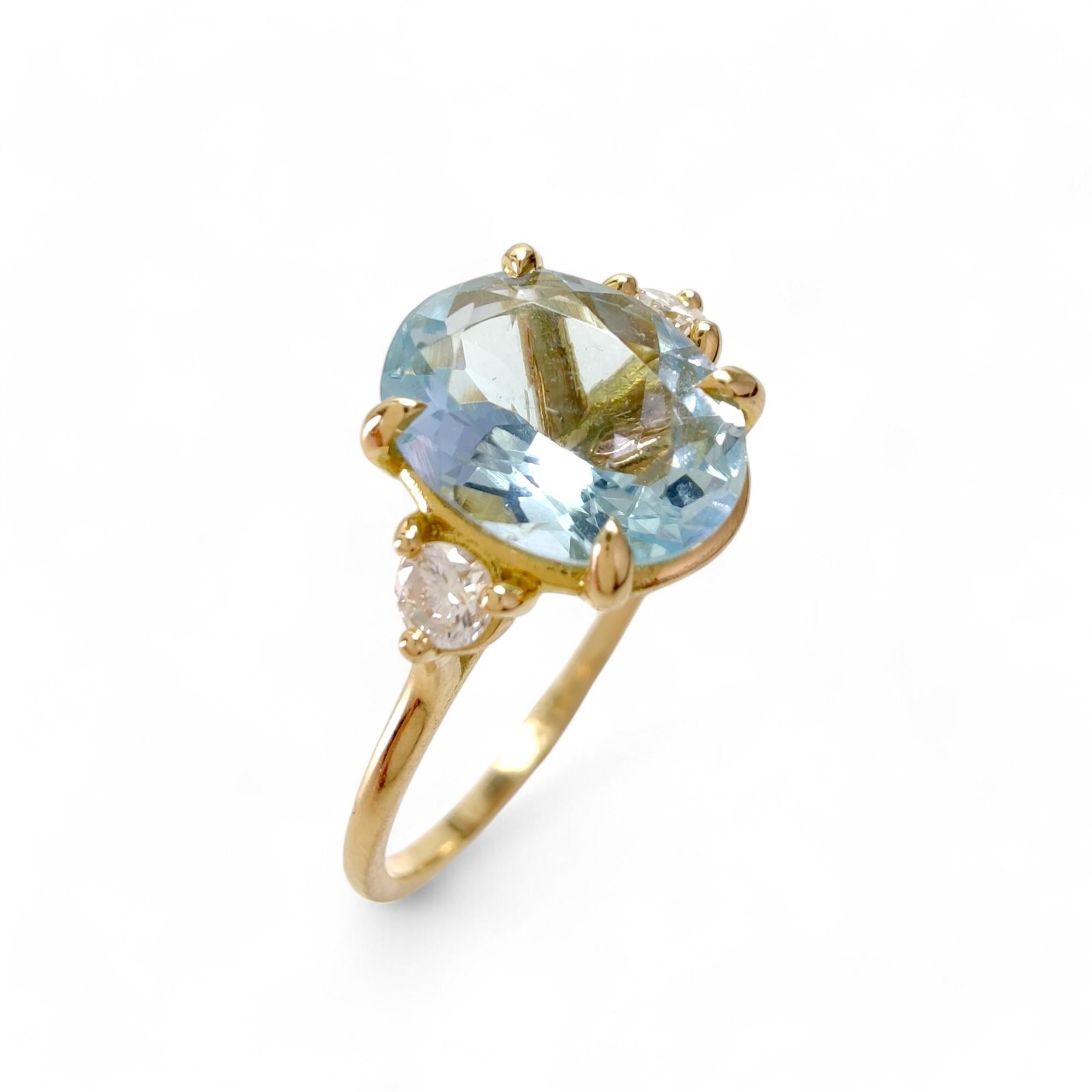 This elegant three-stone ring is crafted in solid 18K gold, blending classic proportions with contemporary elegance. The centerpiece is a natural 1.98ct oval-cut aquamarine, flanked by two natural brilliant-cut diamonds, creating a refined and
