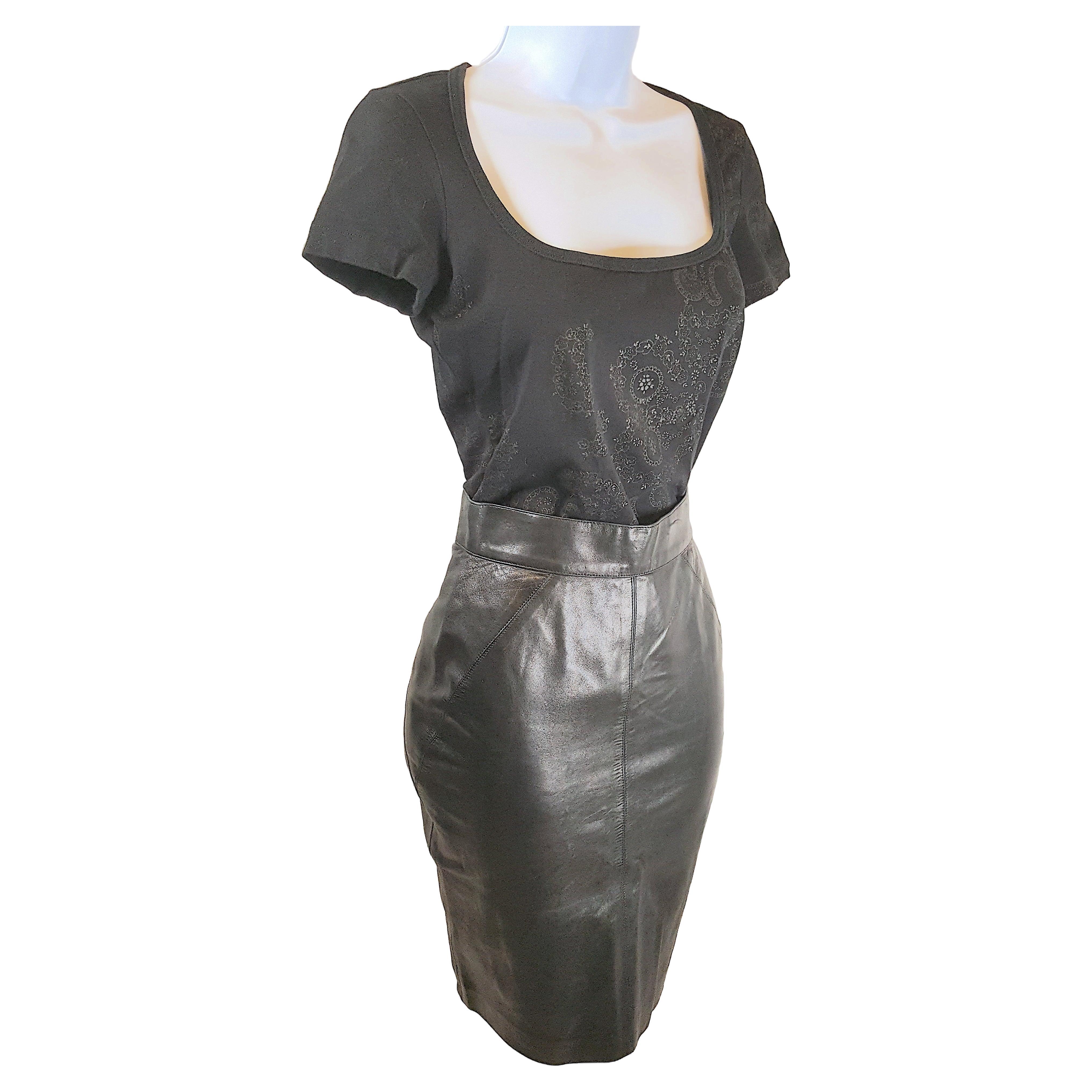 This Alaia Paris black set of a very soft 100% leather high-waisted derriere-enhancing pencil mini skirt and rare logo scoop-neck T-shirt were made around the early 1990s. The stretch top features an asymmetric stenciled shiny screenprint in a