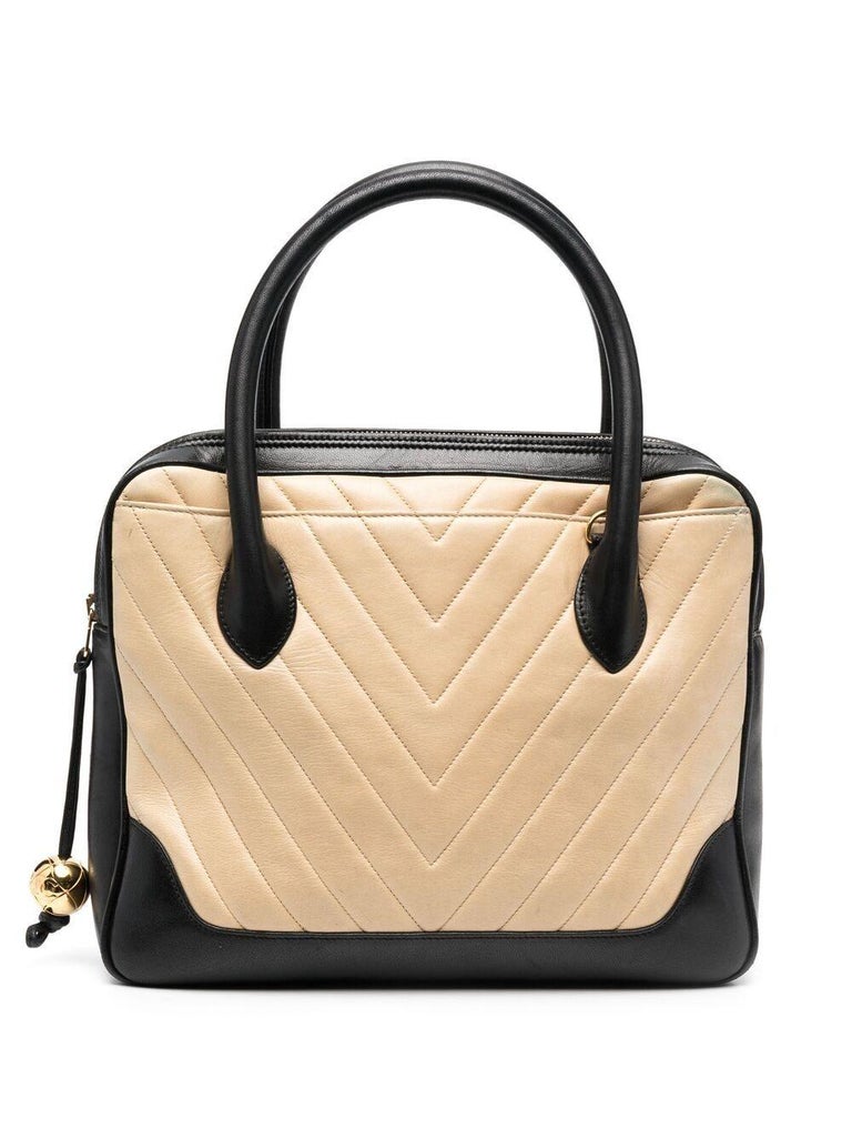 Chanel beige and black quilted leather tote bag featuring a beige chevron quilted,  black leather top handles, gold-tone hardware,  inside pockets, a gold tone round logo detail at zip puller. 
Circa 1989/91. 
Please note that vintage items are not