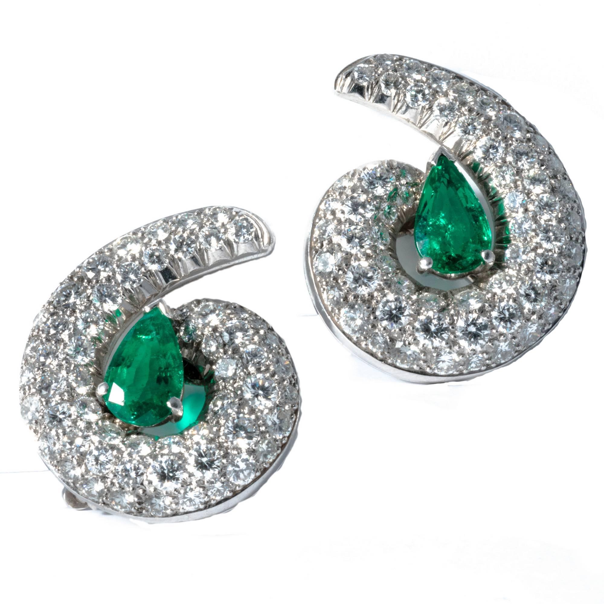 Swirly and bold, these diamond earrings were created in the 1990's in white gold and feature 2 intense vivid green emeralds (approximately carats 1.80) embraced by 114 extra-white diamonds, weighing approximately 3.40 carats.
