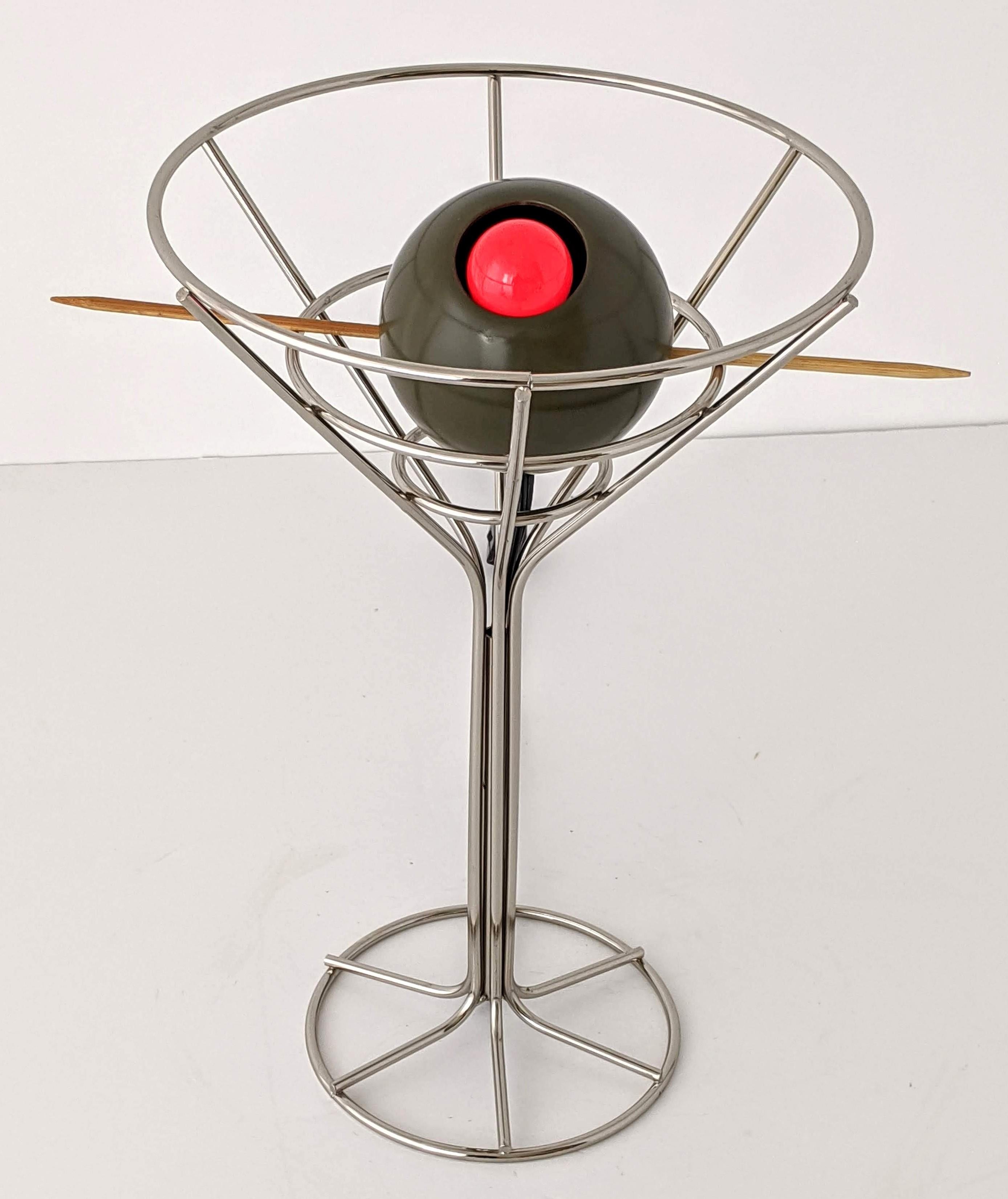 Chromed steel martini glass with red part of olive lighting up. 

Olive could be placed in different position and angle. 

Solid well made construction.

Measures: 14.5 in. high by 9.5 in. wide, stick is 12.5 in. long.

E26 size