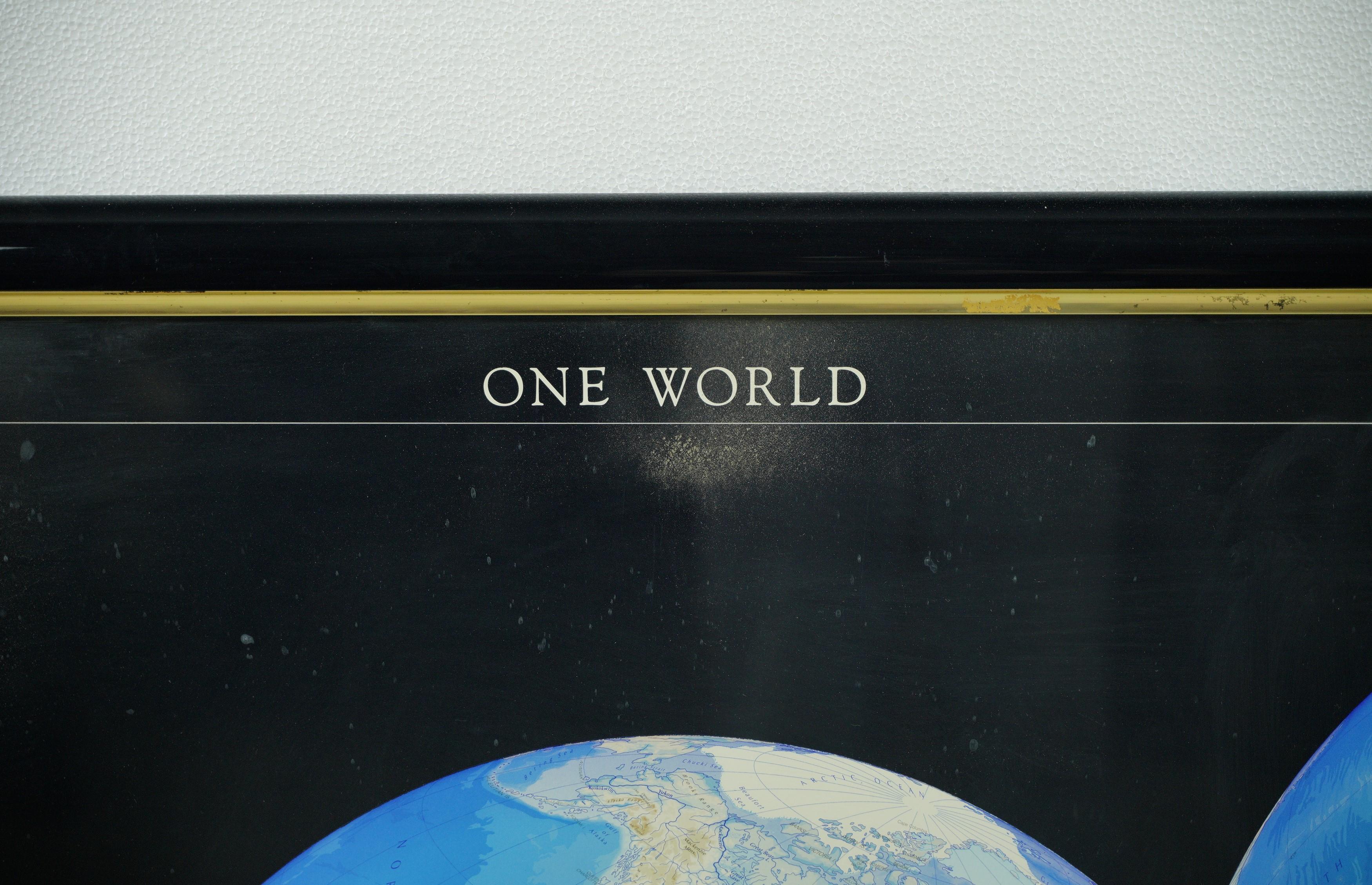 This decorative poster features a map of the Earth with a unique triple perspective view. It is enclosed in a black plastic frame, and the glass covering the poster is still intact. This particular map was produced by Raven Maps & Images in 1990.