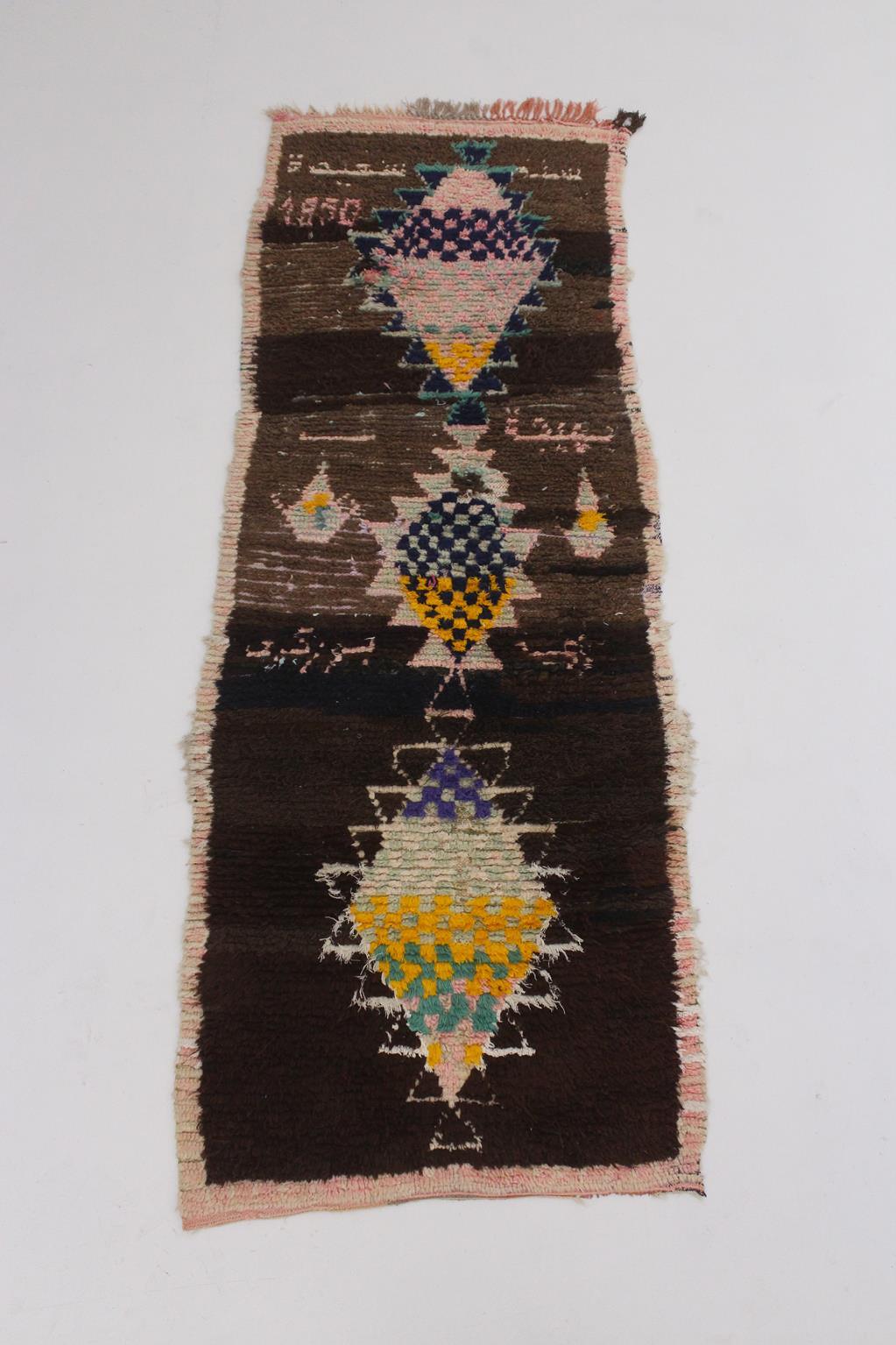 This beautiful vintage runner rug has been sourced in the area of Azilal, High Atlas, Morocco. 

If you look at it closely, you will spot two colorful teapots and names written into it, amongst usual berber designs like diamonds and checks. The name