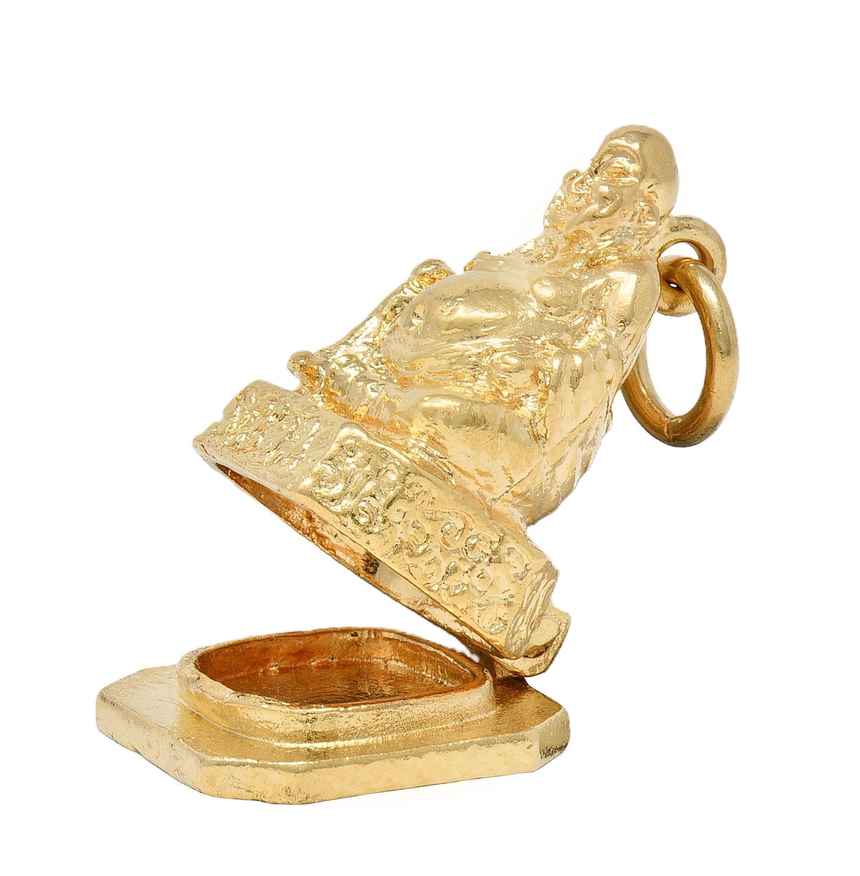 Designed as a highly rendered Buddha statue perched atop pedestal
Accented by grooved details and stone textured base
Base is hinged and opens to reveal a compartment
Completed by jump ring bale
Stamped for 14 karat gold
Fully signed for