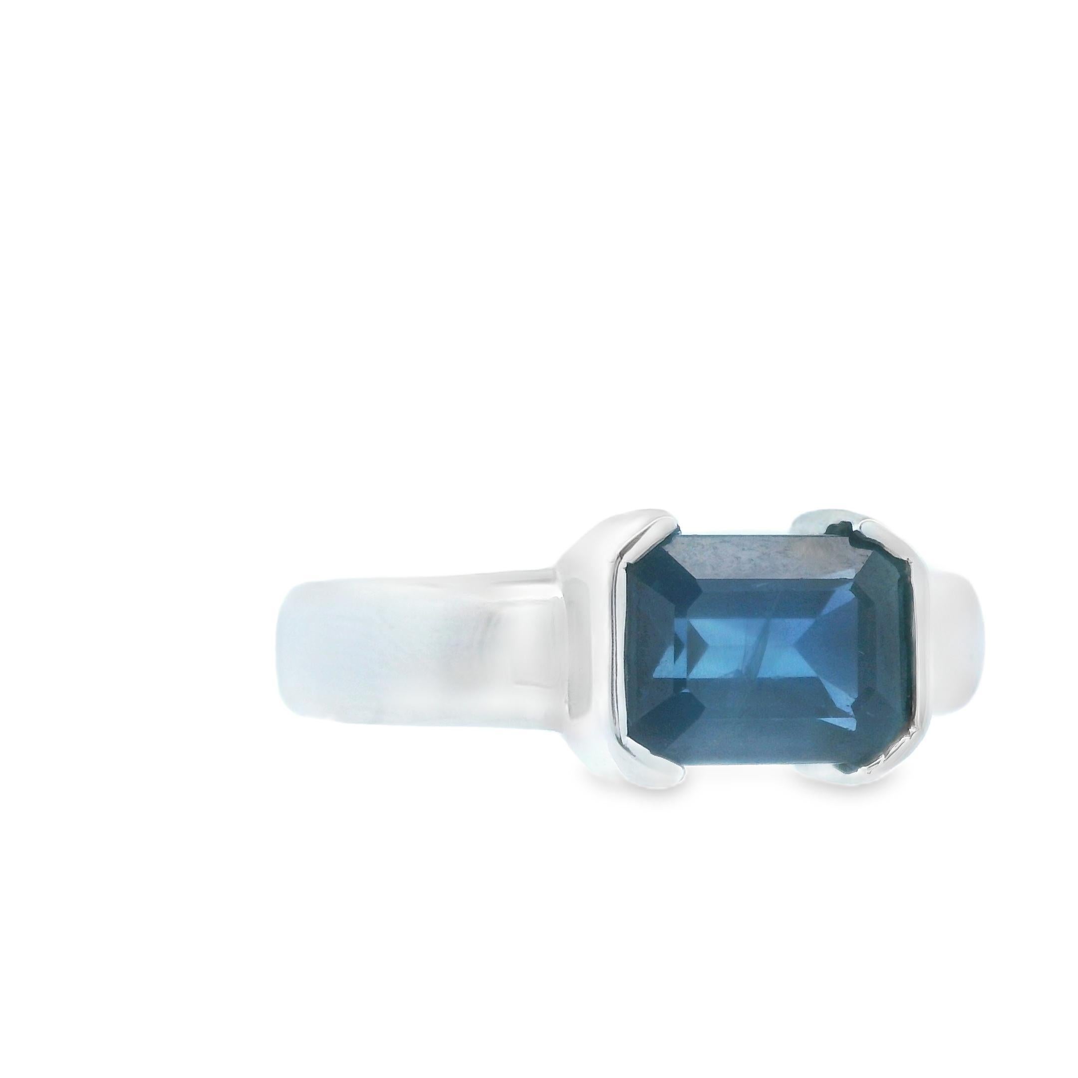 This extravagant ring was made in the 1990s with 14k white gold and natural blue sapphire. The 2.15 carat natural blue sapphire is emerald cut and securely bezel set into the 14k white gold. The bezel setting is known for being extremely secure, and
