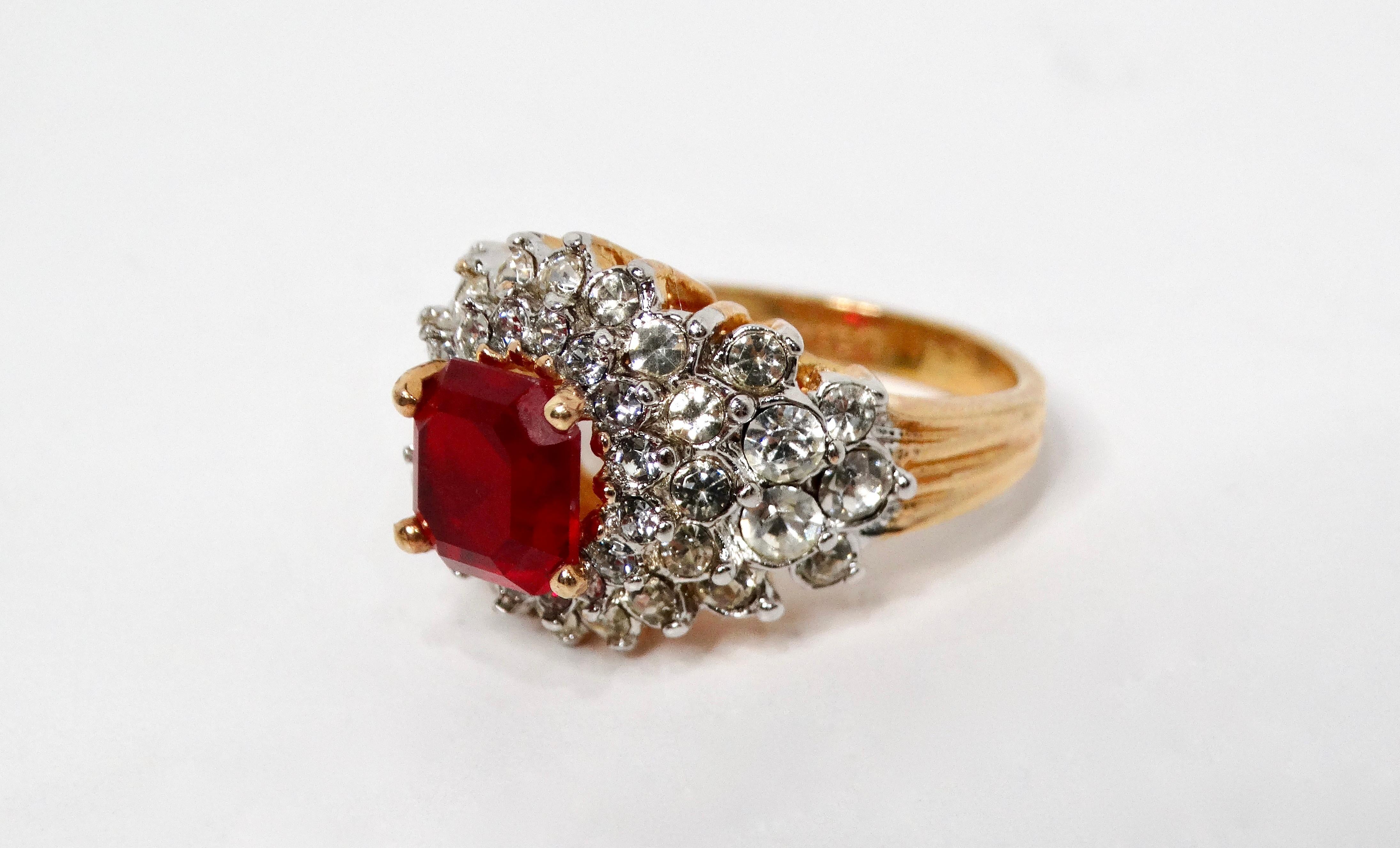 Dieser atemberaubende Cocktailring in 18-karätigem vergoldetem Kristall aus den 1990er Jahren besticht durch seinen Charme und seine Eleganz. Der Ring ist mit einem leuchtend roten synthetischen Rubin verziert und wird von einer Gruppe schimmernder