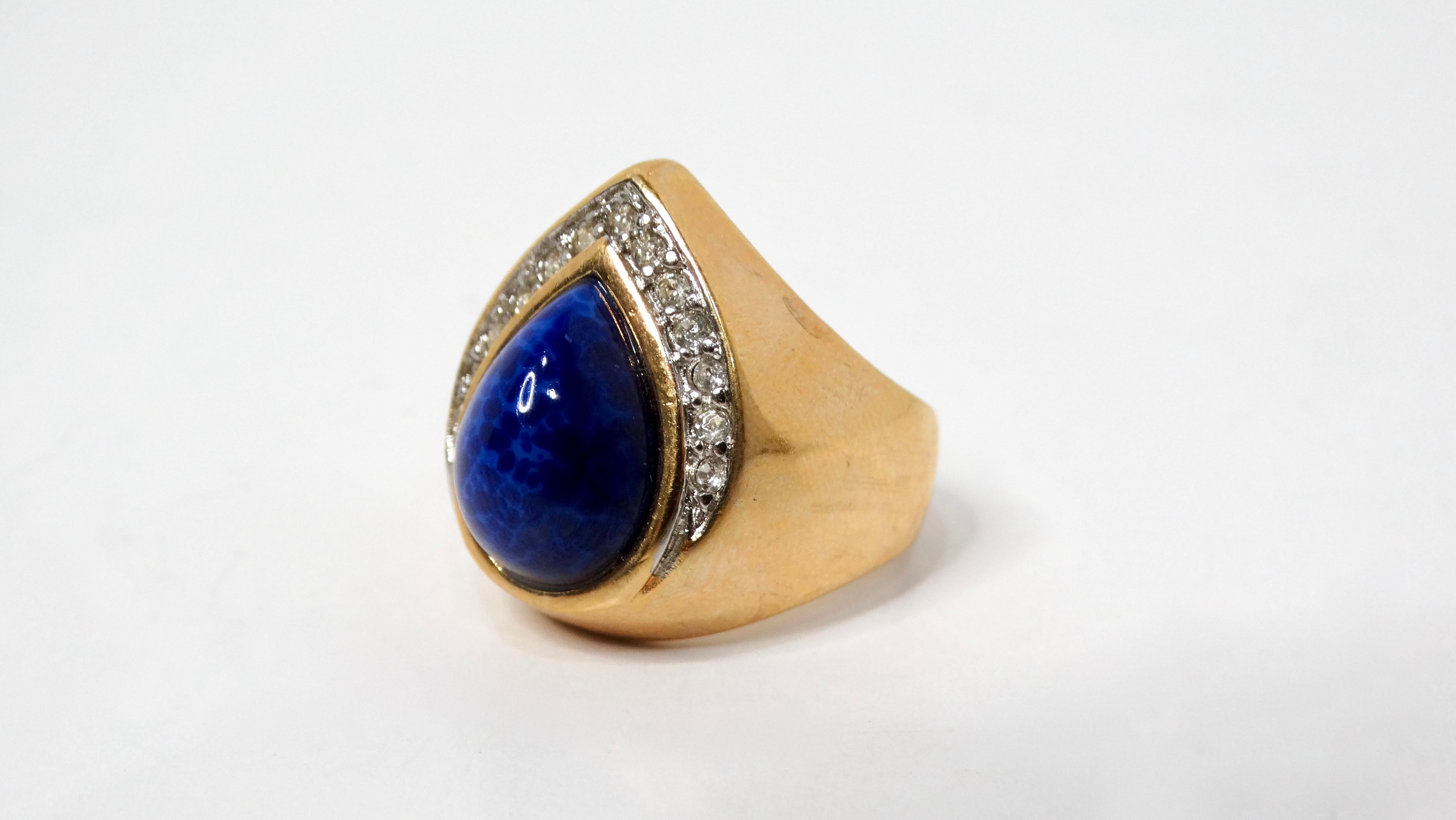 This stunning 18k gold plated ring is a true showstopper, featuring a teardrop-shaped purple costume stone at its center. The rich, vibrant color of the stone is expertly paired with a halo of sparkling crystals that add a touch of sophistication