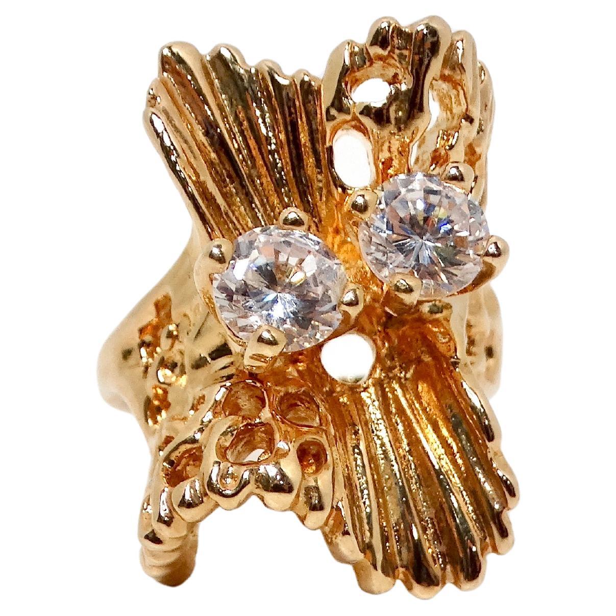 The 1990s Abstract Nature 18k Gold Plated & Crystal Cocktail Ring is a stunning piece of jewelry that embodies the essence of the natural world. Its unique, organic design resembles a branch of coral or a chunk of driftwood, evoking the beauty of
