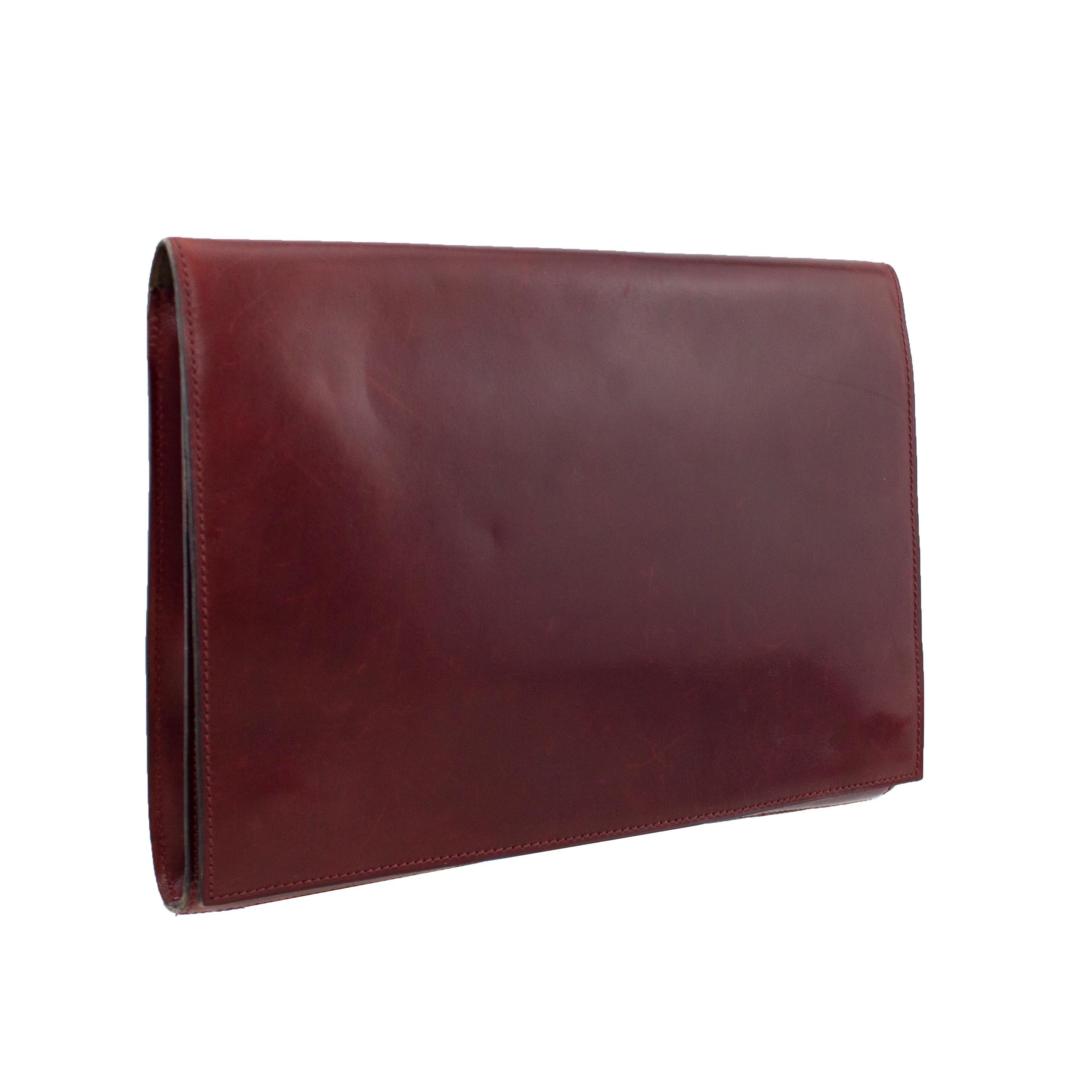 Sleek and chic supple polished maroon leather Alaïa portfolio from the 1990s. Rectangular with a large front flap that closes with two large interior magnetic snaps. Interior of flap is brown suede with gold Alaïa brand stamps. Interior compartment