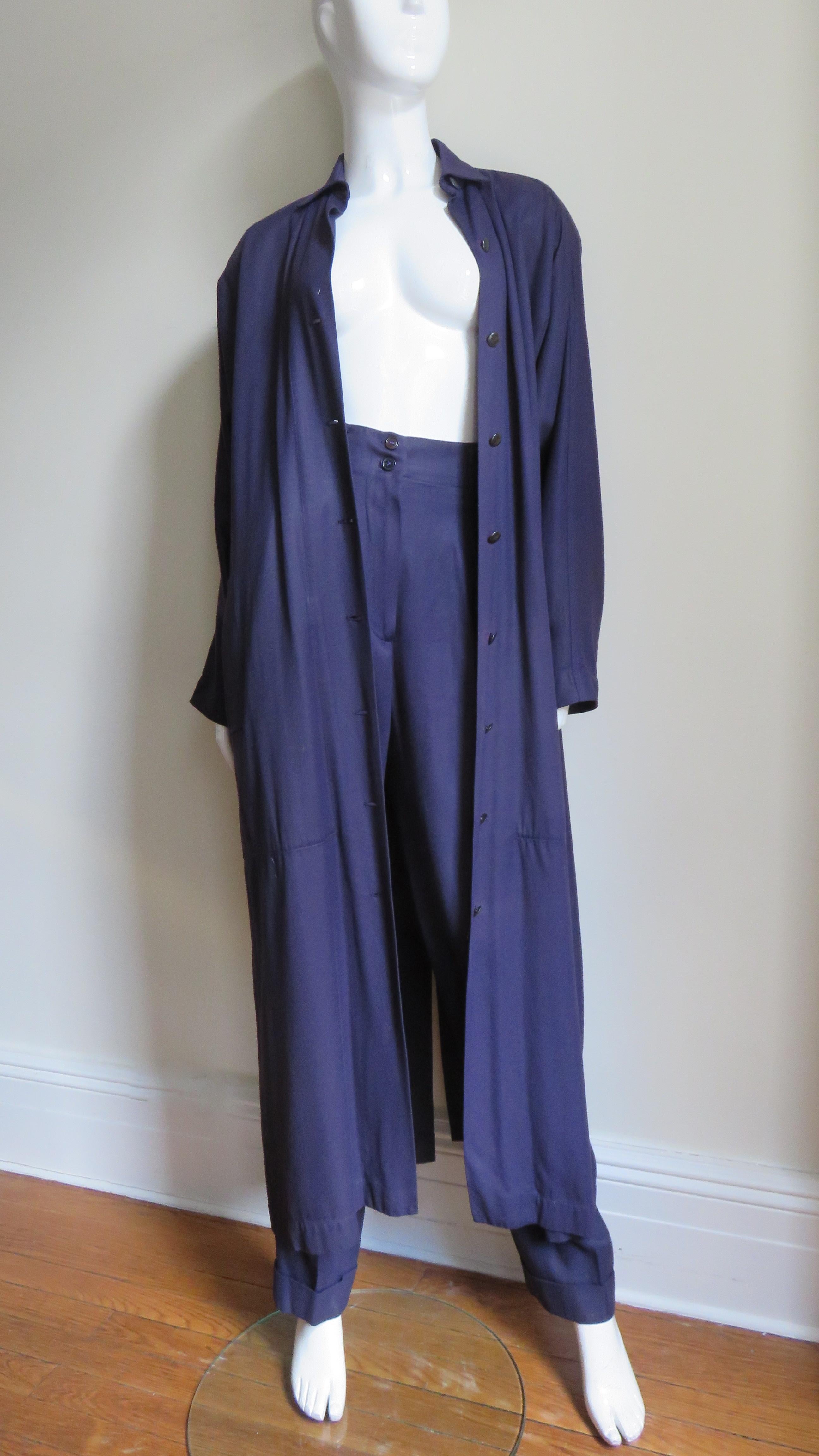A fabulous eggplant purple long coat and pants set from Azzedine Alaia.  The long duster coat has a collar, black metal buttons up the front, padded shoulders, dolman sleeves, side seam pockets and a deep slit at the back hem.  The pants have full
