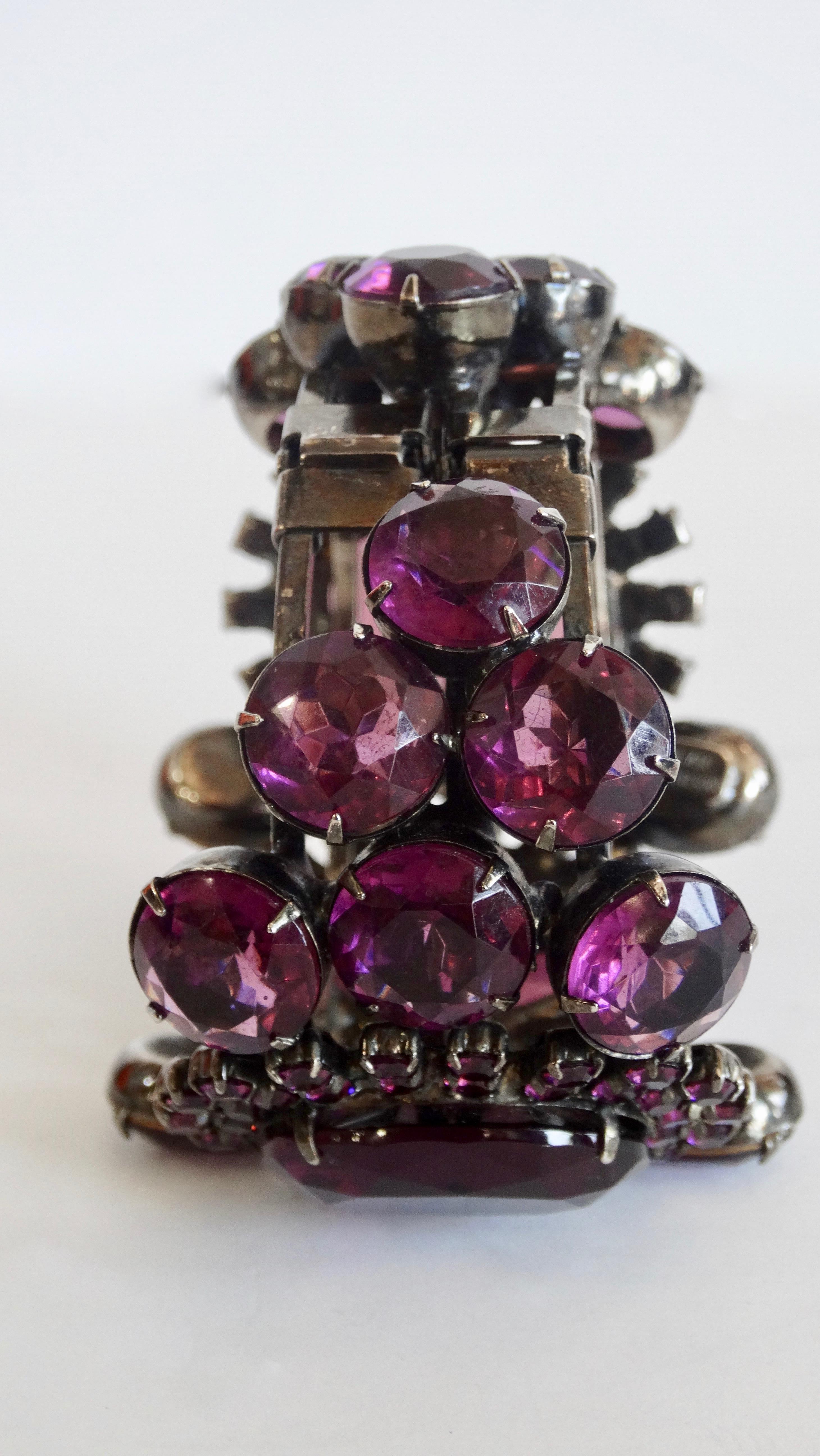 Elegance is key! And this Alan Anderson cuff is sure to elevate your collection! Circa 1990s, this art deco inspired cuff is embellished with a variety of purple vintage rhinestones and is finished in a The clamper has been plated in a gun metal
