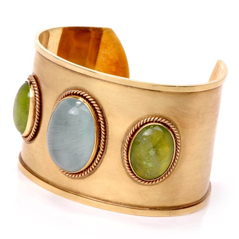 This stylish late 1980's estate peridot aquamarine cuff bracelet is crafted in solid 18K yellow gold.

This wide cuff bracelet features 3 bezel set gems adorned with rope gold bezel.

The center cabochon cut aquamarine approx. 31.06 carats is