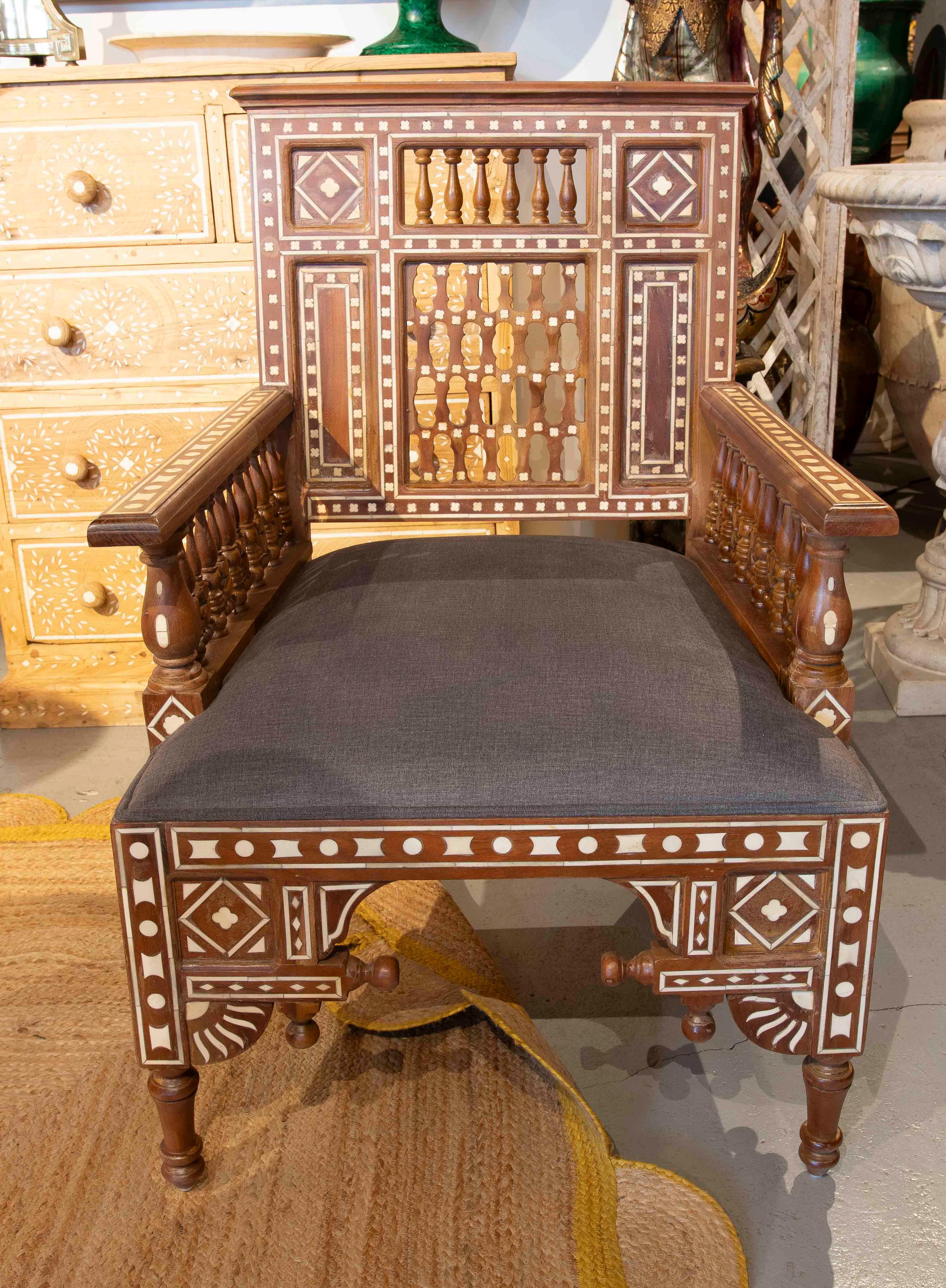 Majestic, poltrona artigianale di ispirazione araba, realizzata in legno massiccio intagliato con squisiti intarsi che ne esaltano il design geometrico e ornamentale. La sua struttura robusta ed elegante è decorata con una combinazione di dettagli