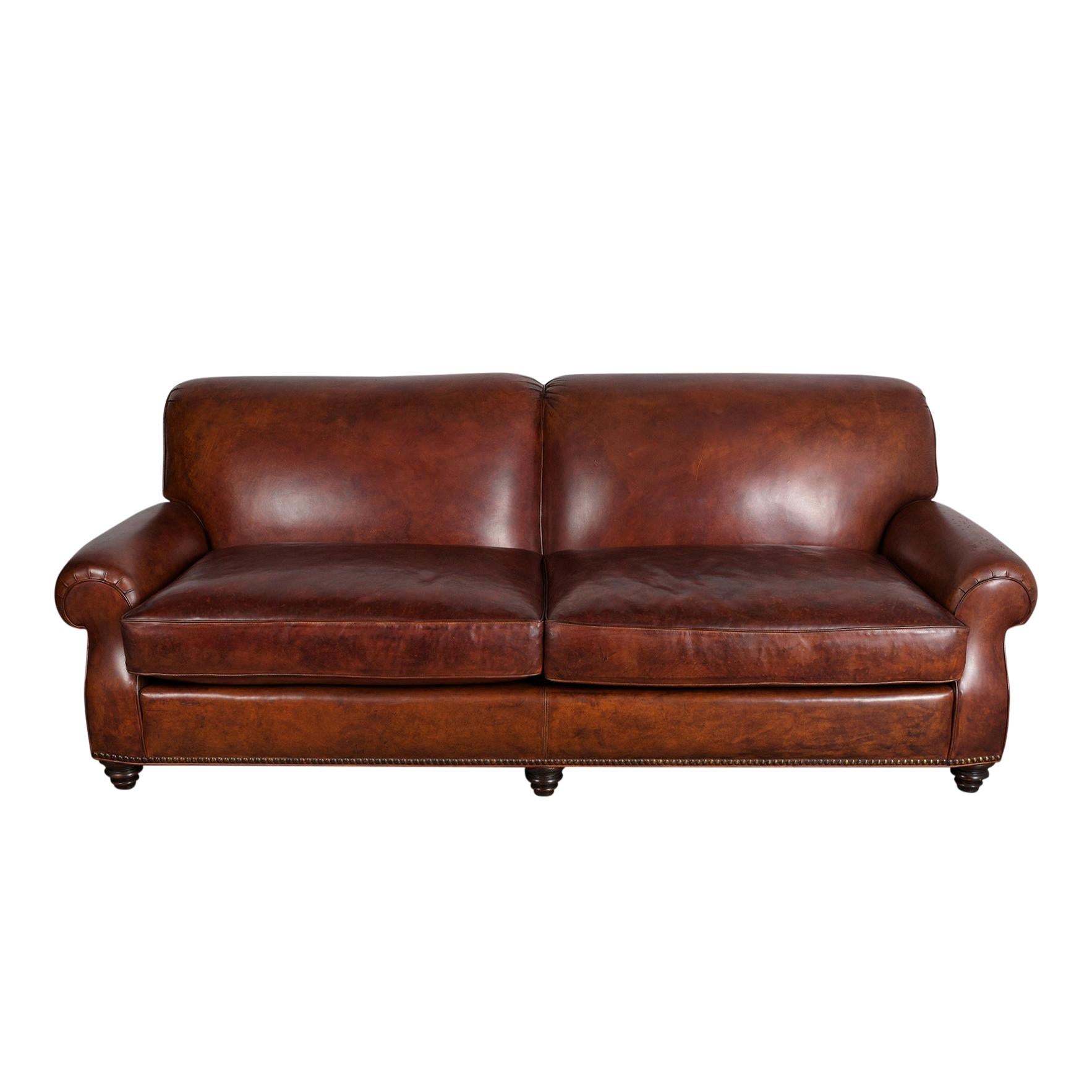 This vintage leather sofa is in great condition and is upholstered in its original rich brown color leather in great condition and has a beautiful patina finish. This sofa also features round armrests, two large seat cushions with single piping
