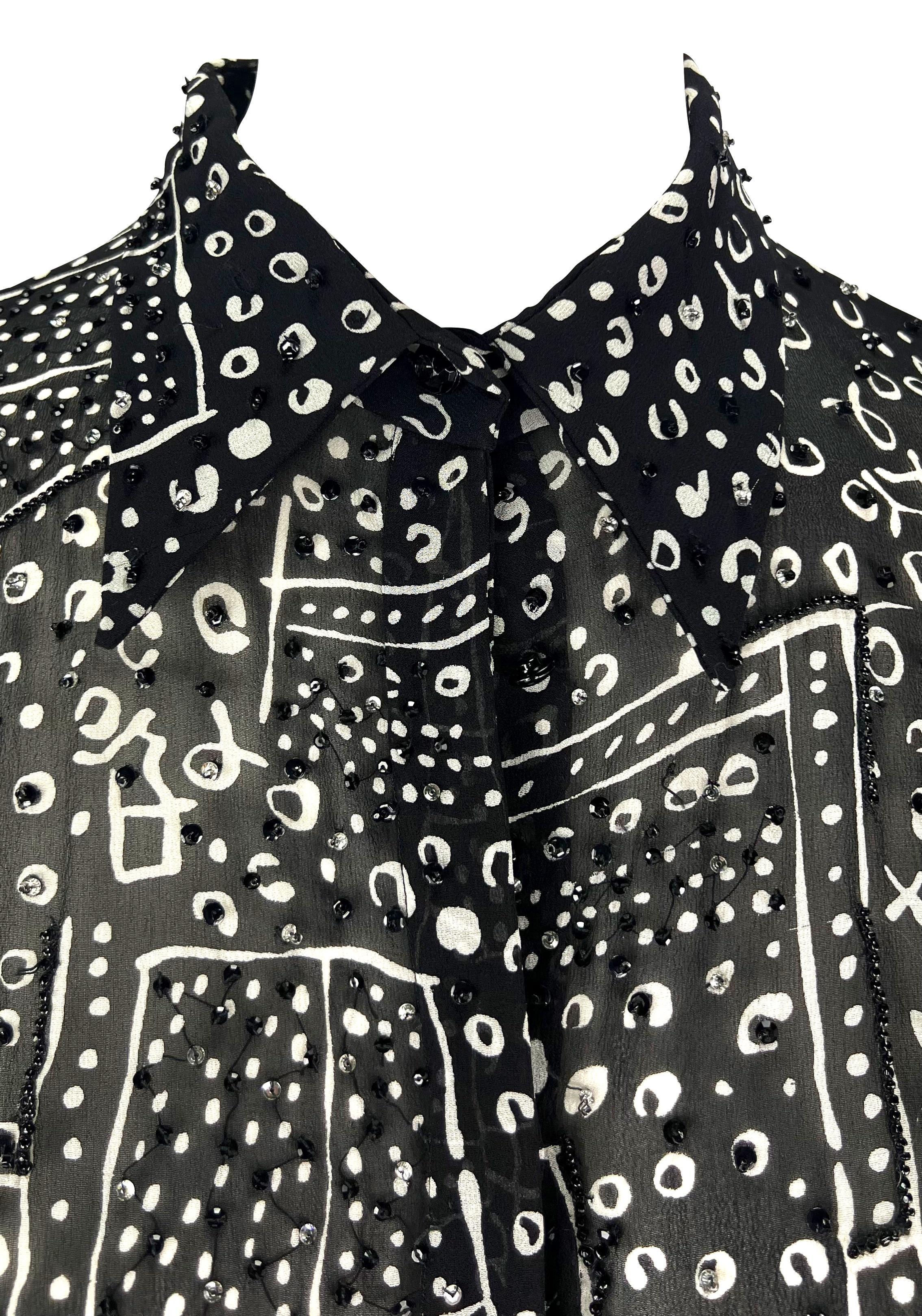 Ti presentiamo un top astratto e chic in bianco e nero di Atelier Versace, disegnato da Donatella Versace. Dagli anni '90, questo elegante top nero trasparente presenta un motivo astratto bianco con accenti di perline a mano. Questa camicia Atelier