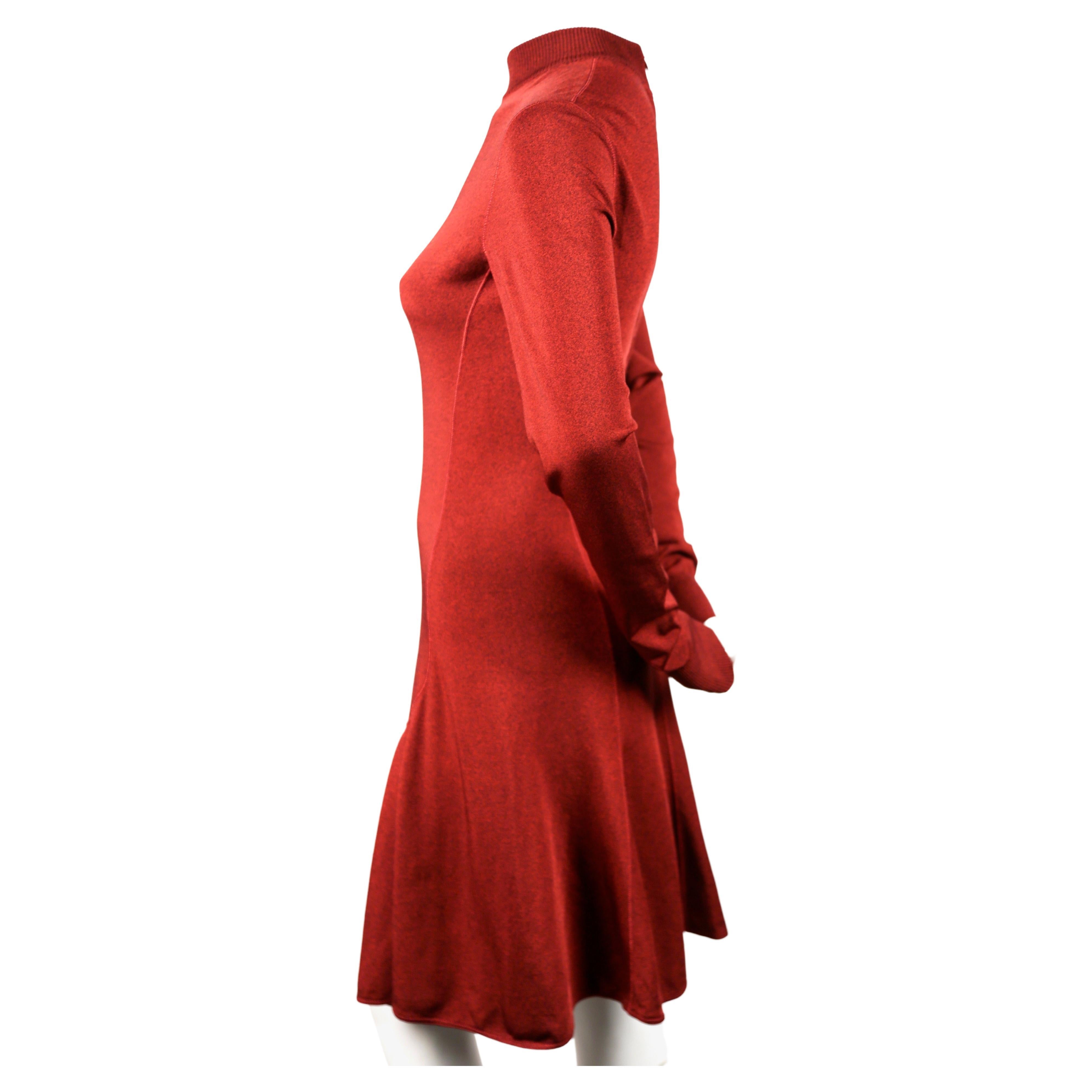 Dark-red, flared dress with high neckline and long sleeves designed by Azzedine Alaia dating to the early 1990's. No size indicated best fits a S or M. Approximate measurements (unstretched): shoulder 15