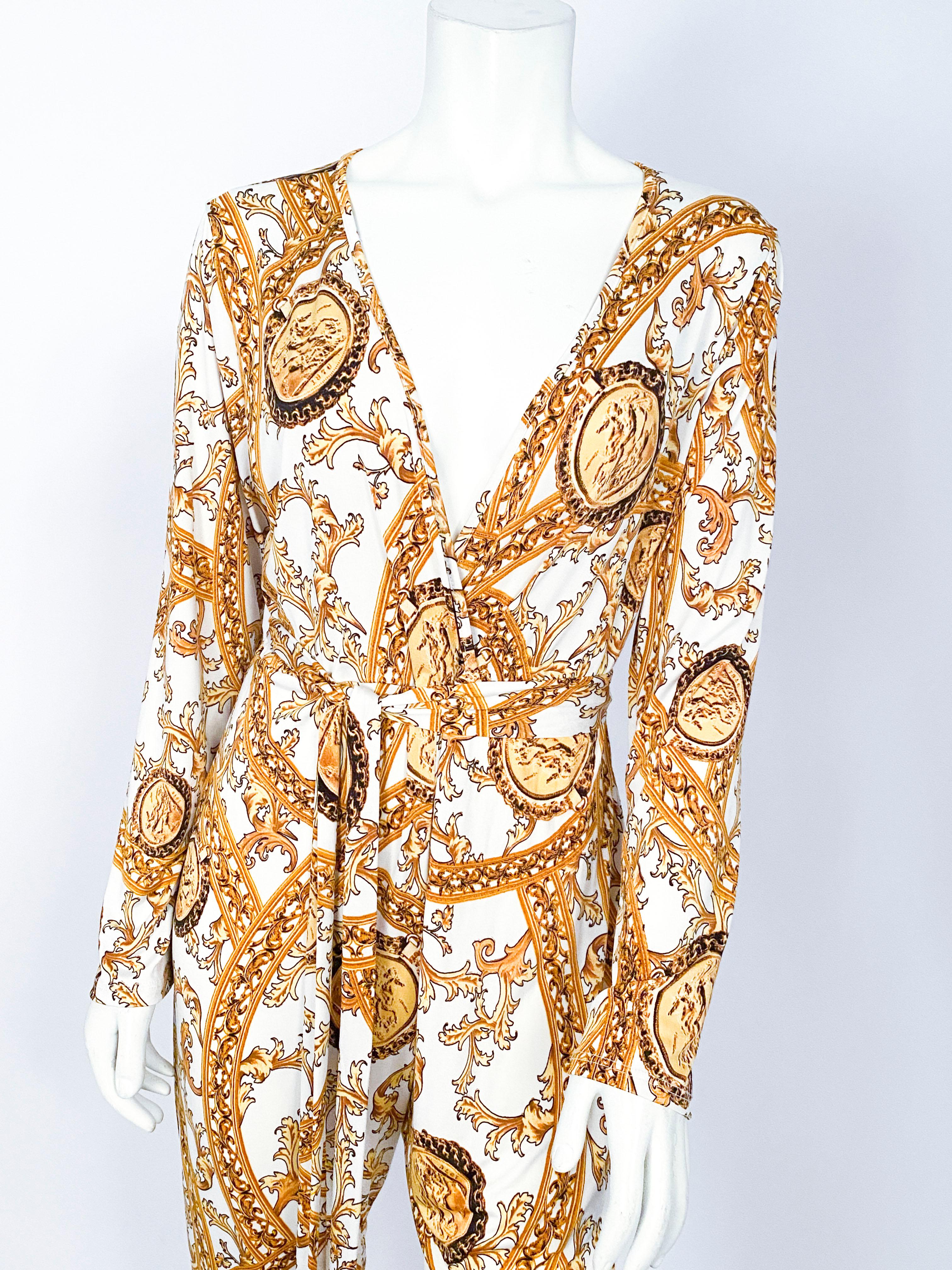 1990s jumpsuit featuring a bold baroque/rococo coin print in gold tones. The waist is cinched with a full length sash and the bodice is a faux wrap around. 