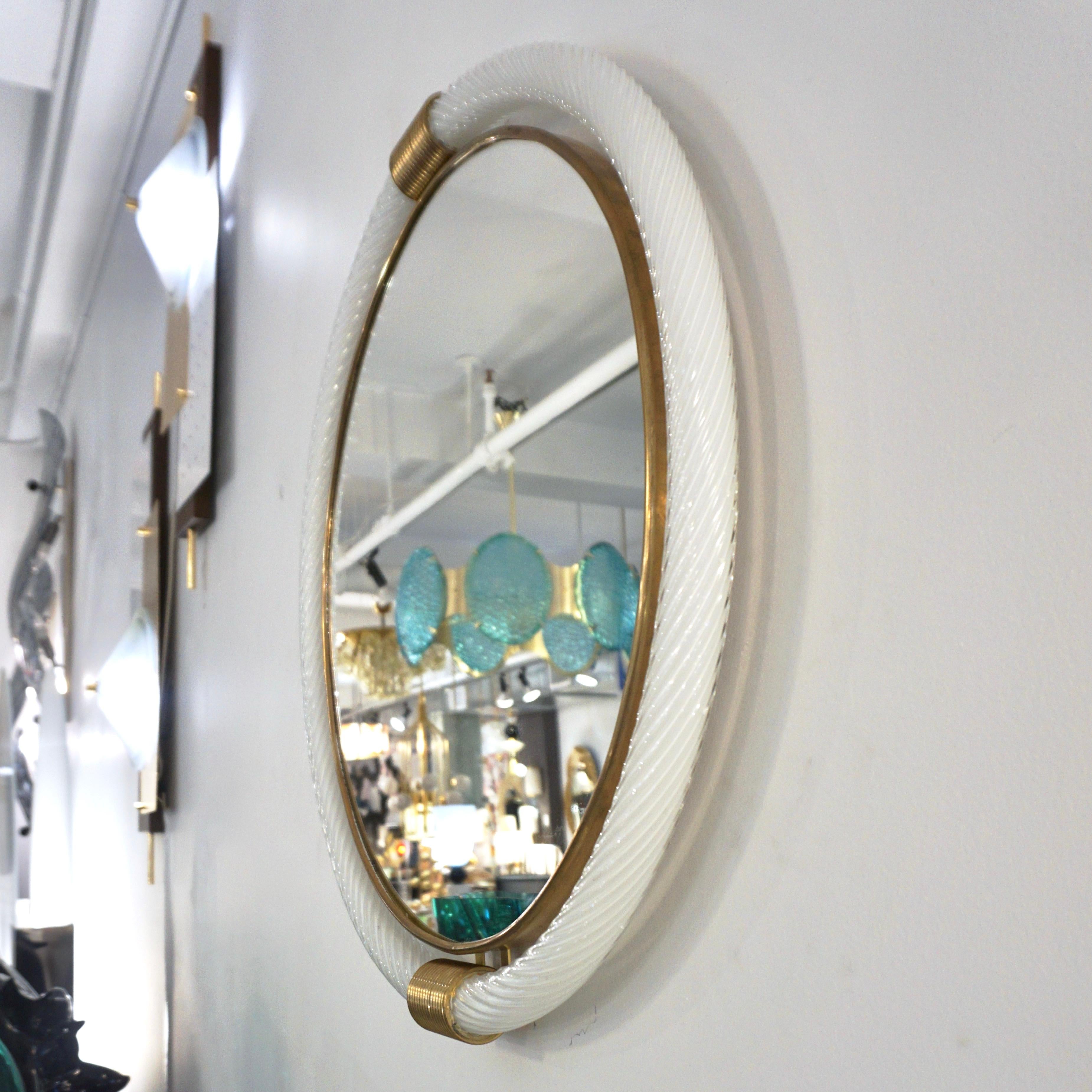 A unique organic round mirror attributed to Barovier & Toso, an ideal size as a solution to brighten up and enlarge a small space, entrance, powder room, office, corridor... The central mirror plate, edged in brass, is embraced by a blown Murano