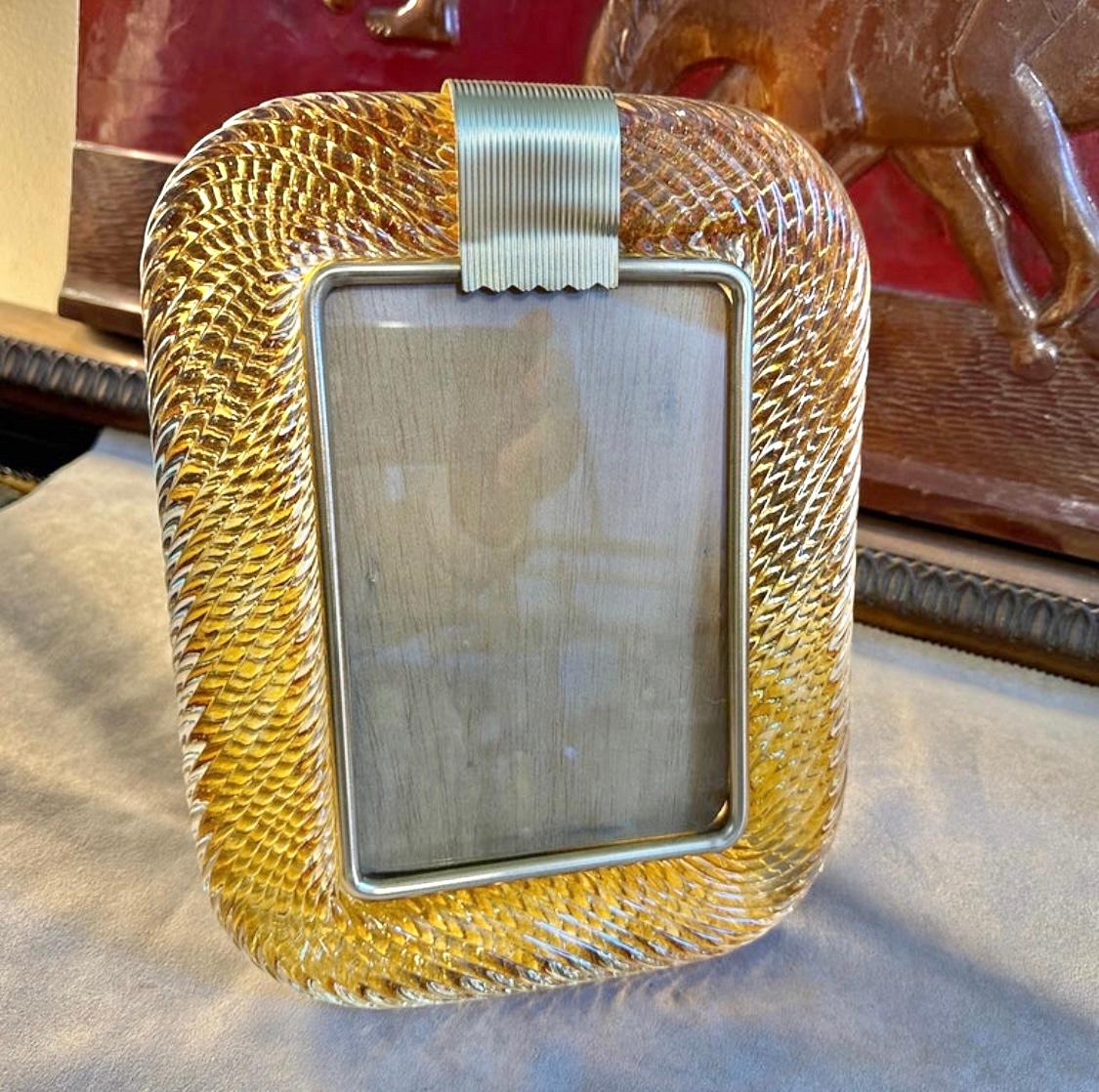 An amber Murano glass picture frame designed and manufactured in Venice in the style of Barovier in lovely condition. The vintage photo frame is a beautiful and elegant piece of decor that is perfect for displaying your favorite memories in style.