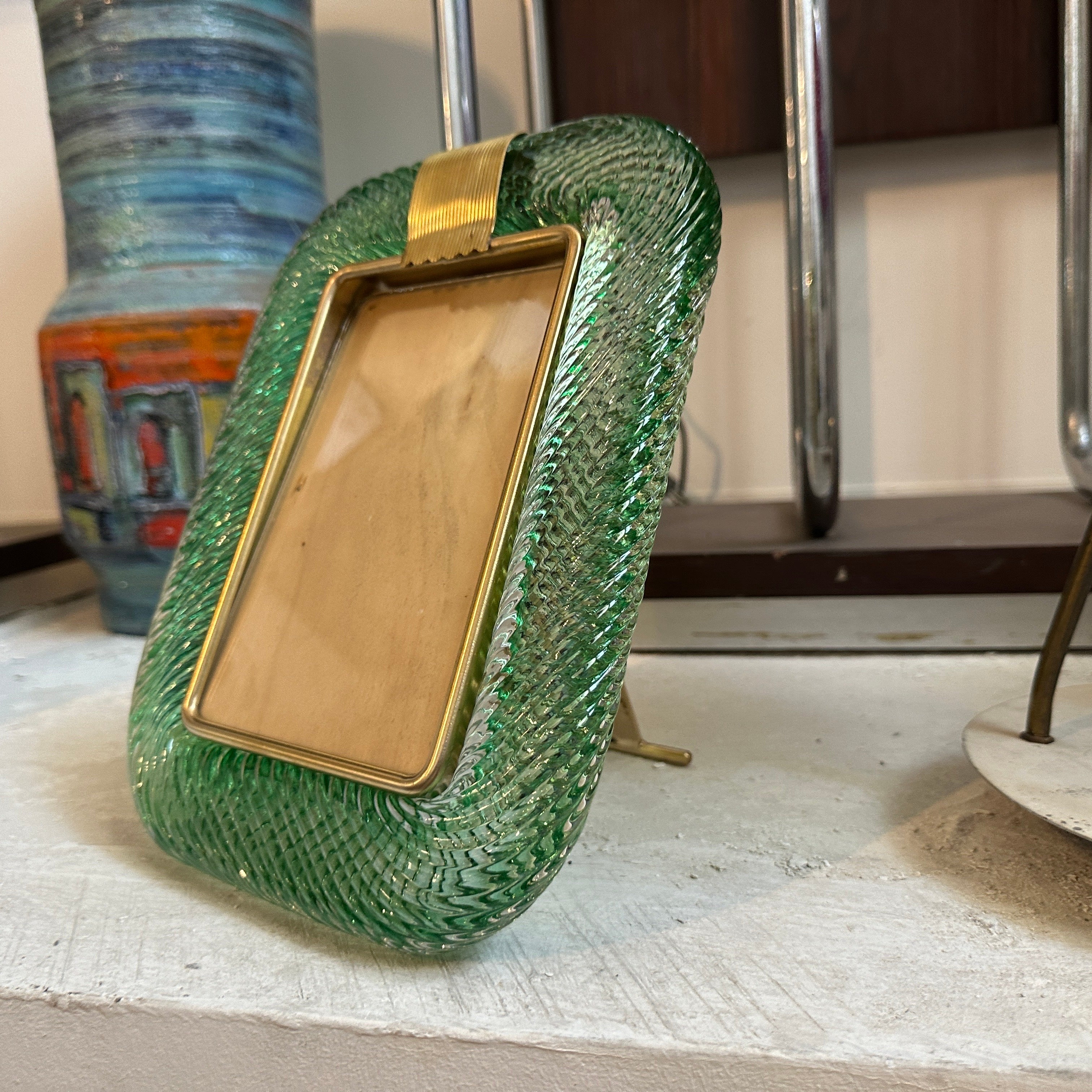 A light green murano glass picture frame designed and manufactured in Venice in the style of Barovier, it's in lovely conditions. The vintage photo frame is a beautiful and elegant piece of decor that is perfect for displaying your favorite memories