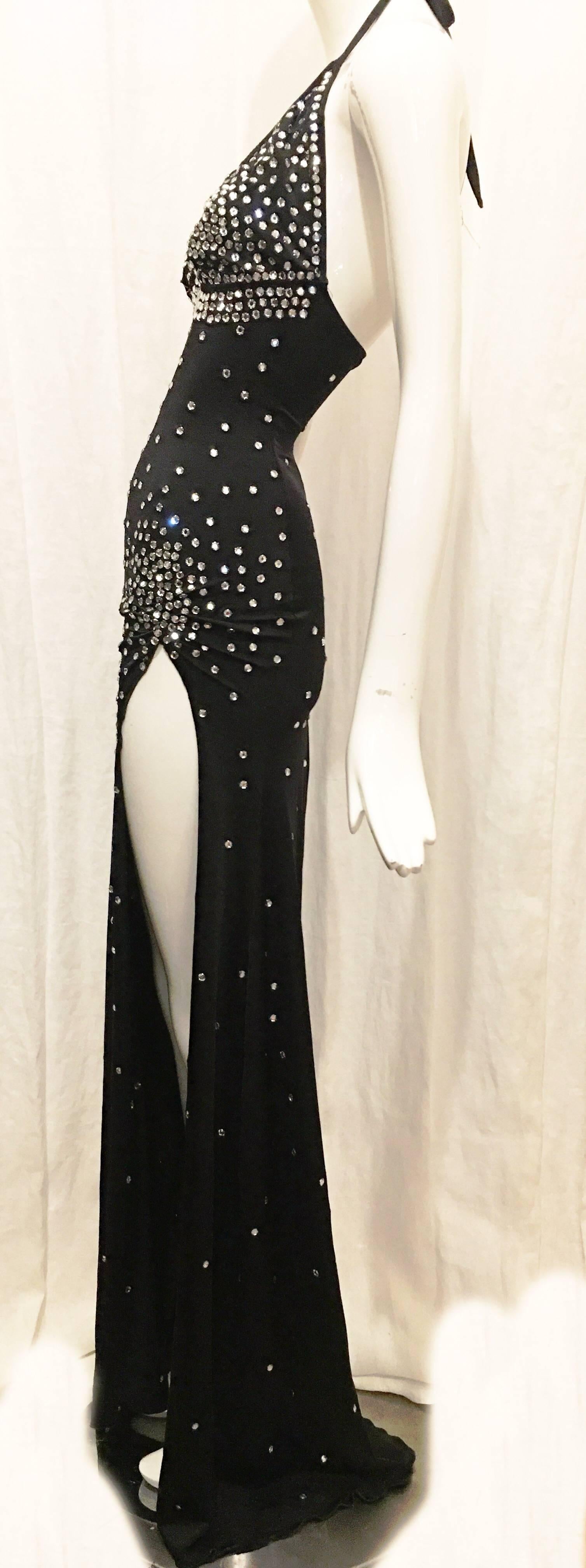 Full length black halter dress with all-over rhinestone embellishment. Concentration of rhinestones around bust and at left hip with more scattered rhinestones throughout. 43 inch slit at left hip adds an extra sexy touch to this form fitting eye