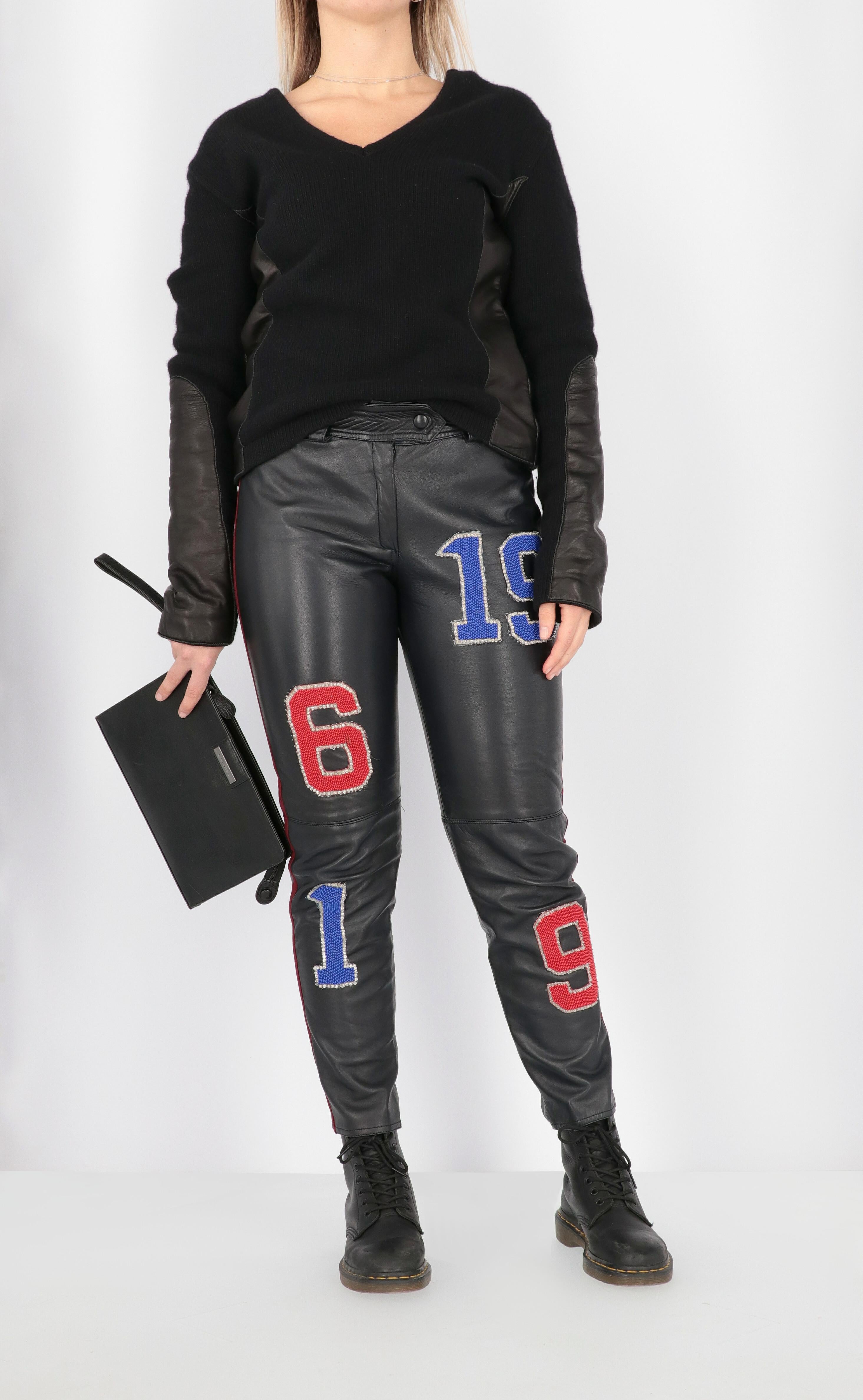 Blumarine by Anna Molinari genuine black leather straight trousers with burgundy side band and front beads embroidered in number shapes. Front closure with button and zip, belt loops and front welt pockets.

The product has some missing beads as
