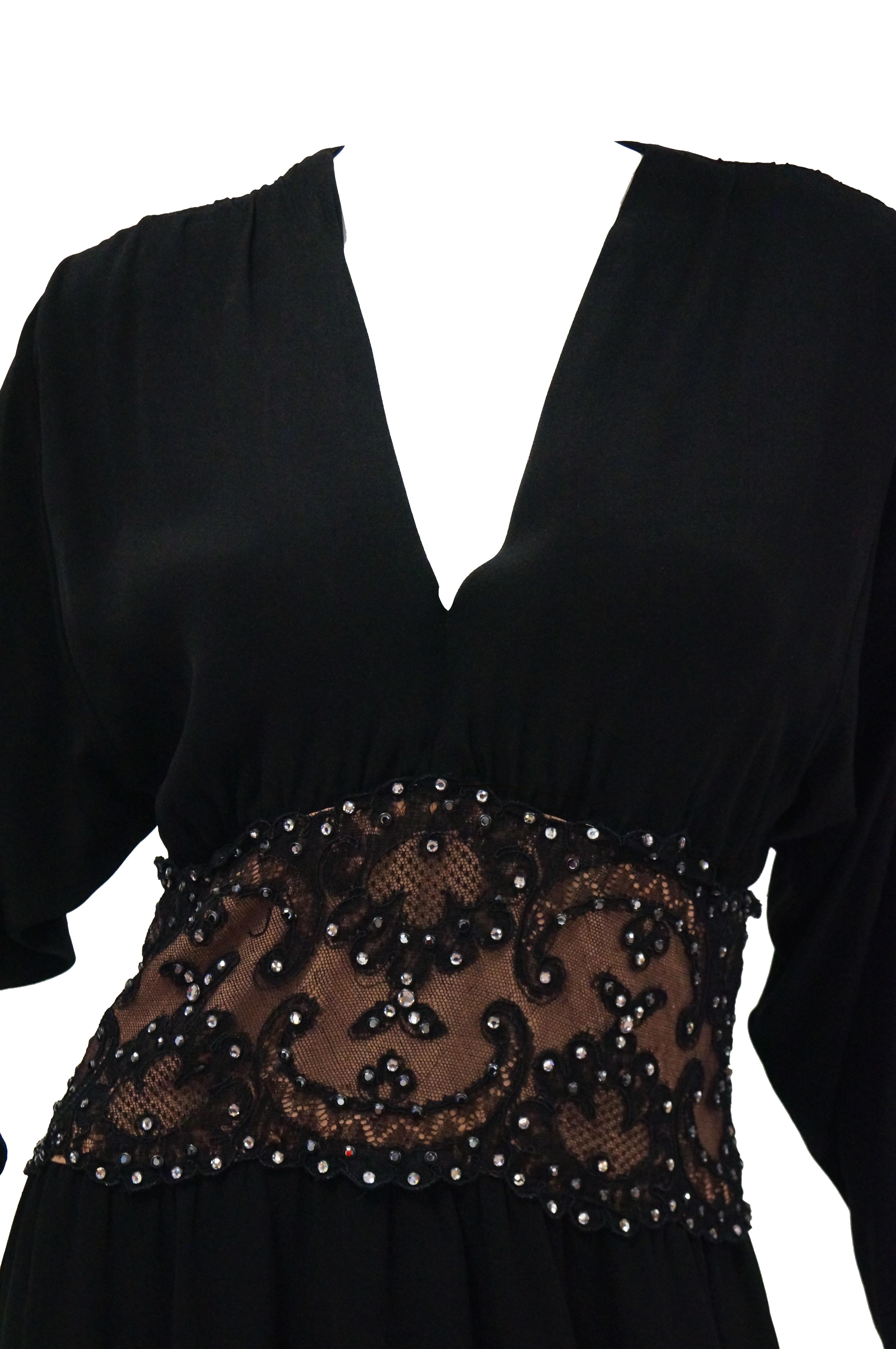 Stunning black silk cocktail dress by Bob Mackie. The dress falls at the knee, has long batwing sleeves with a narrow cuff, a plunging V - neckline, and a loose pencil skirt. The dress has a cinched waist accented by a wide lace band over a peach