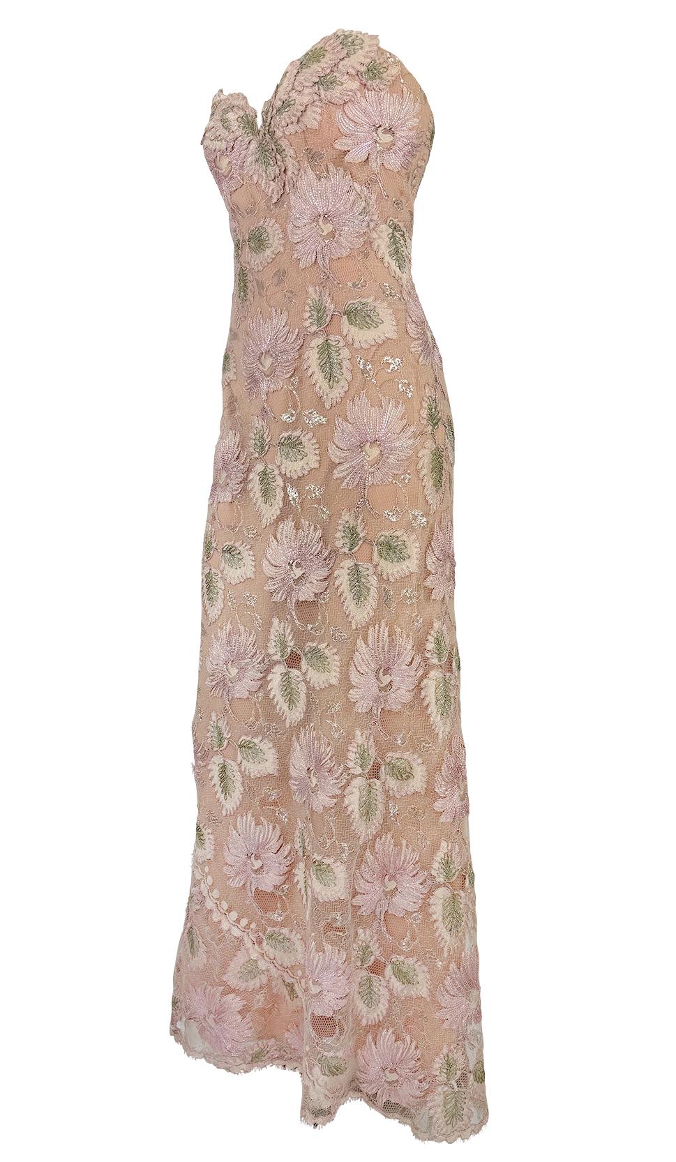 This 1990s strapless gown by Bob Mackie features a sheer peach lace base embroidered with oversized lilac and sage floral motifs in metallic Lurex thread. The sweetheart neckline and fitted silhouette highlight the body, while the allover embroidery