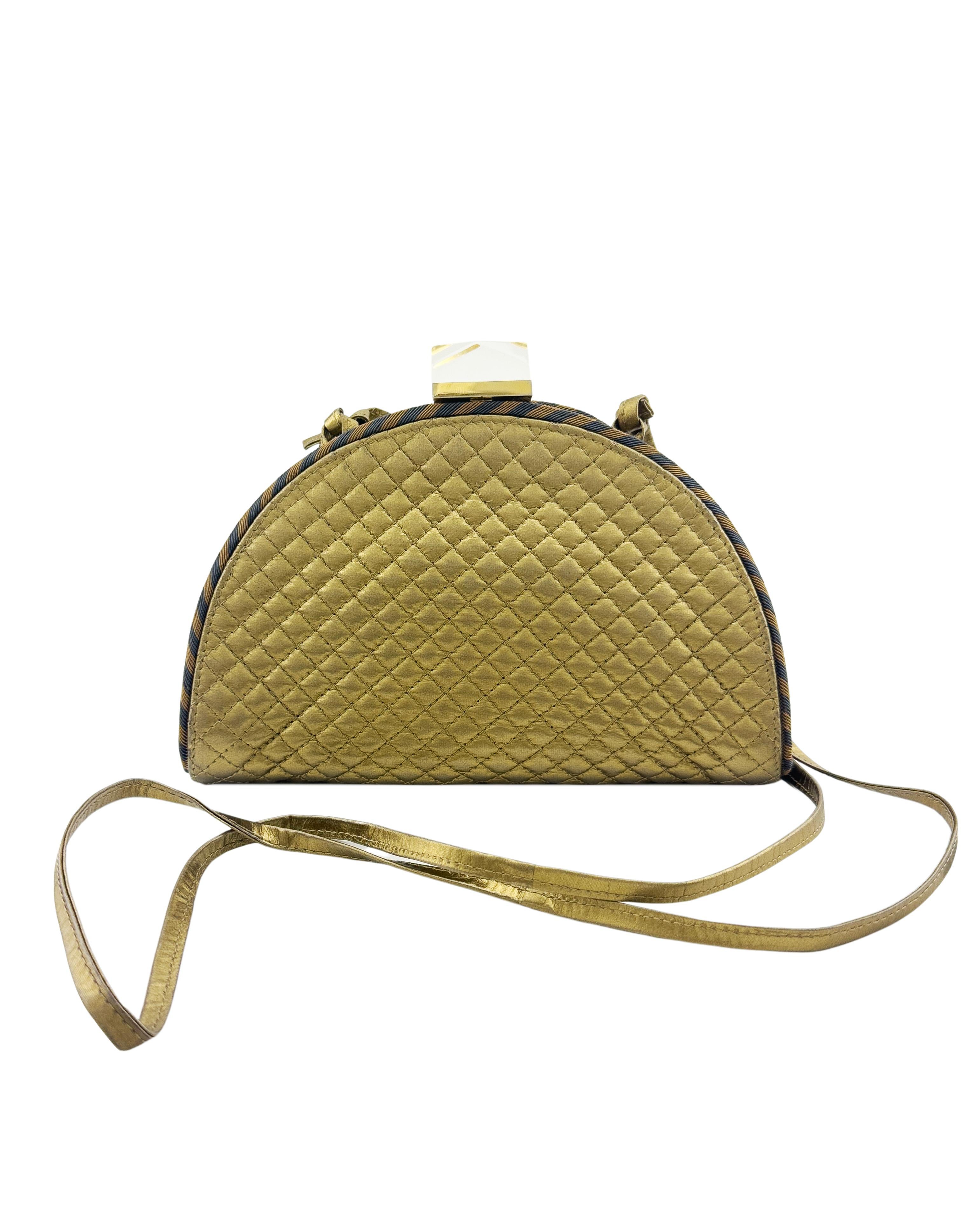 Bottega Veneta demi lune shaped clutch from the 1990s. Gold silk quilted exterior with a black and brown striped grosgrain trim. Snap closure with a large crystal shaped clear lucite and gold tone metal clasp. Optional thin gold leather long