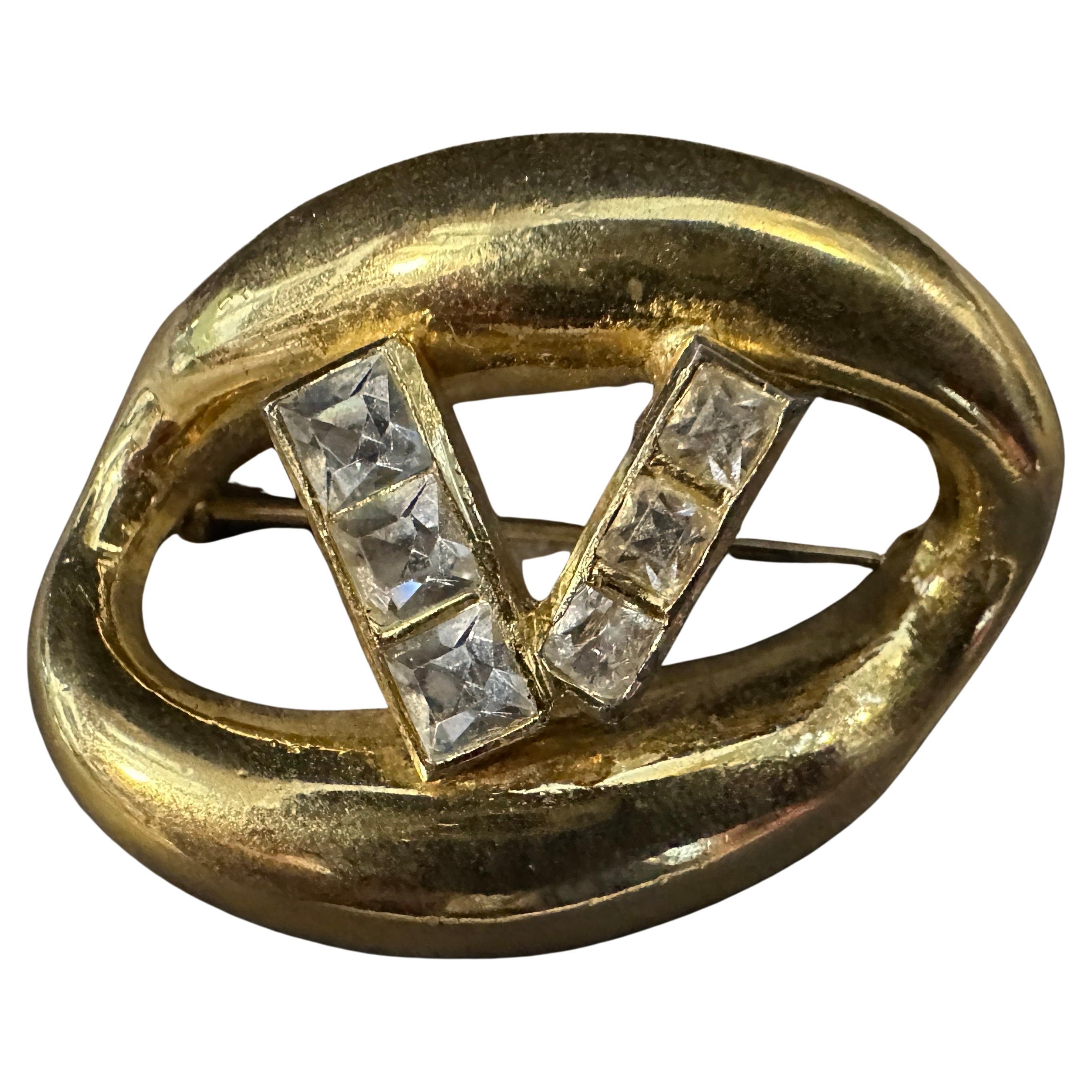 Cette broche à logo Valentino des années 1990 est un accessoire raffiné et élégant, réalisé en laiton avec une luxueuse finition dorée. Le design présente une forme abstraite, ovale, avec des bords lisses et incurvés, créant une silhouette