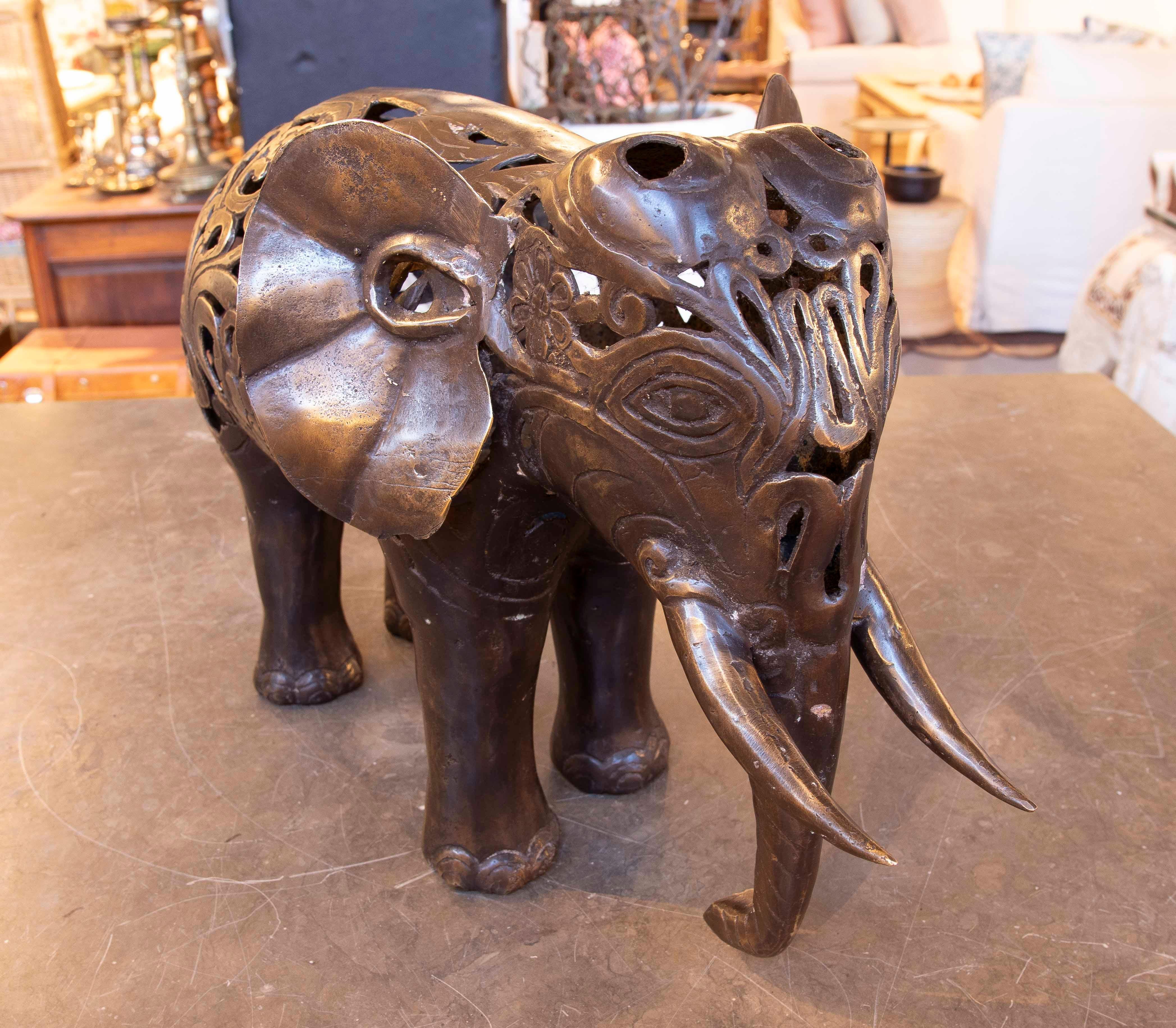 Cette étonnante sculpture d'éléphant en bronze présente un design ajouré mêlant motifs floraux et stylisés. La pièce se distingue par ses détails complexes, qui donnent une impression de légèreté visuelle au matériau robuste. Les défenses sculptées