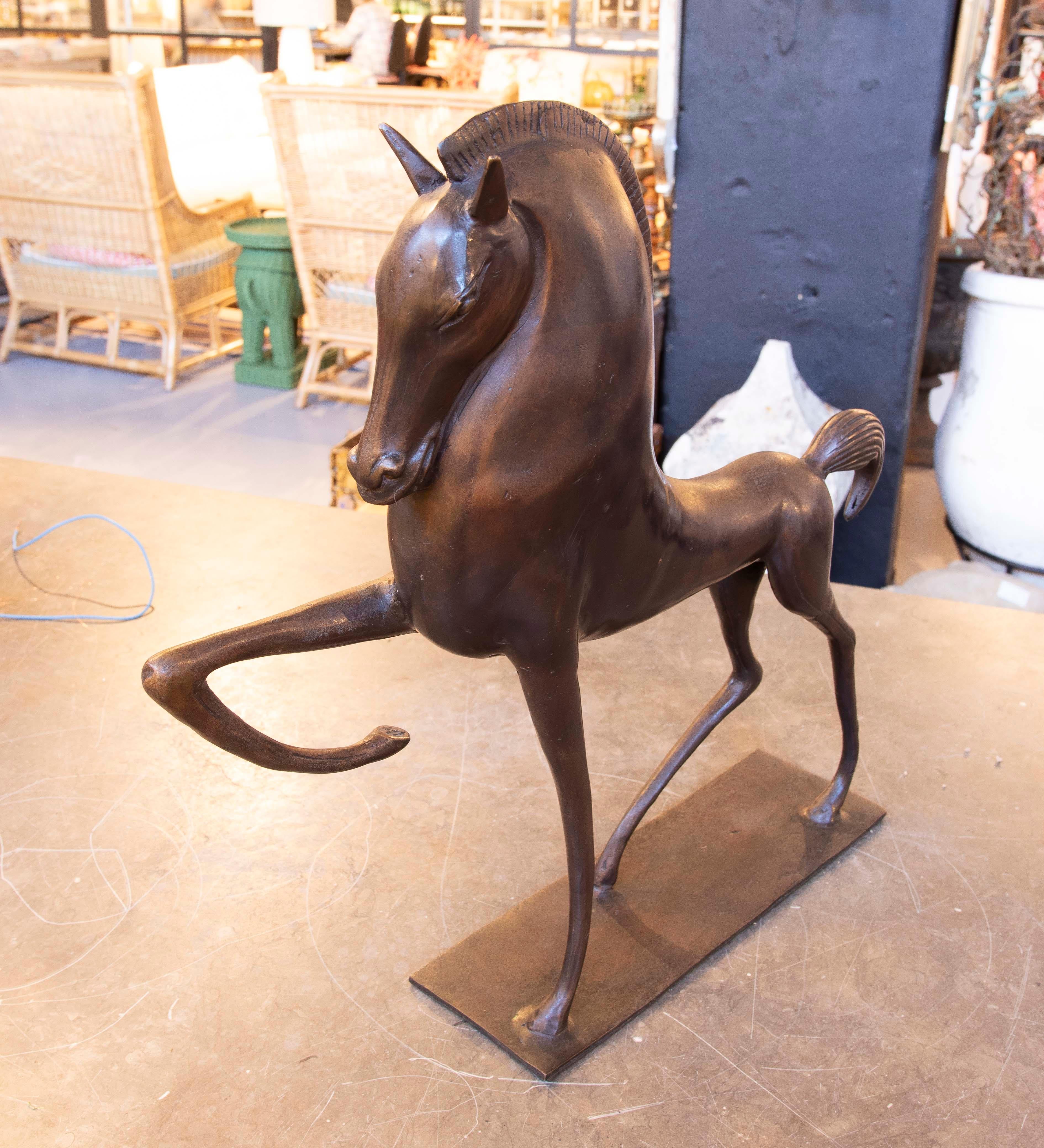 This refined bronze sculpture captures a horse in a dynamic pose, emphasizing its strength and grace. The detailed design features a stylized mane and flowing lines, lending a modern character to this artistic piece. Mounted on a rectangular base,