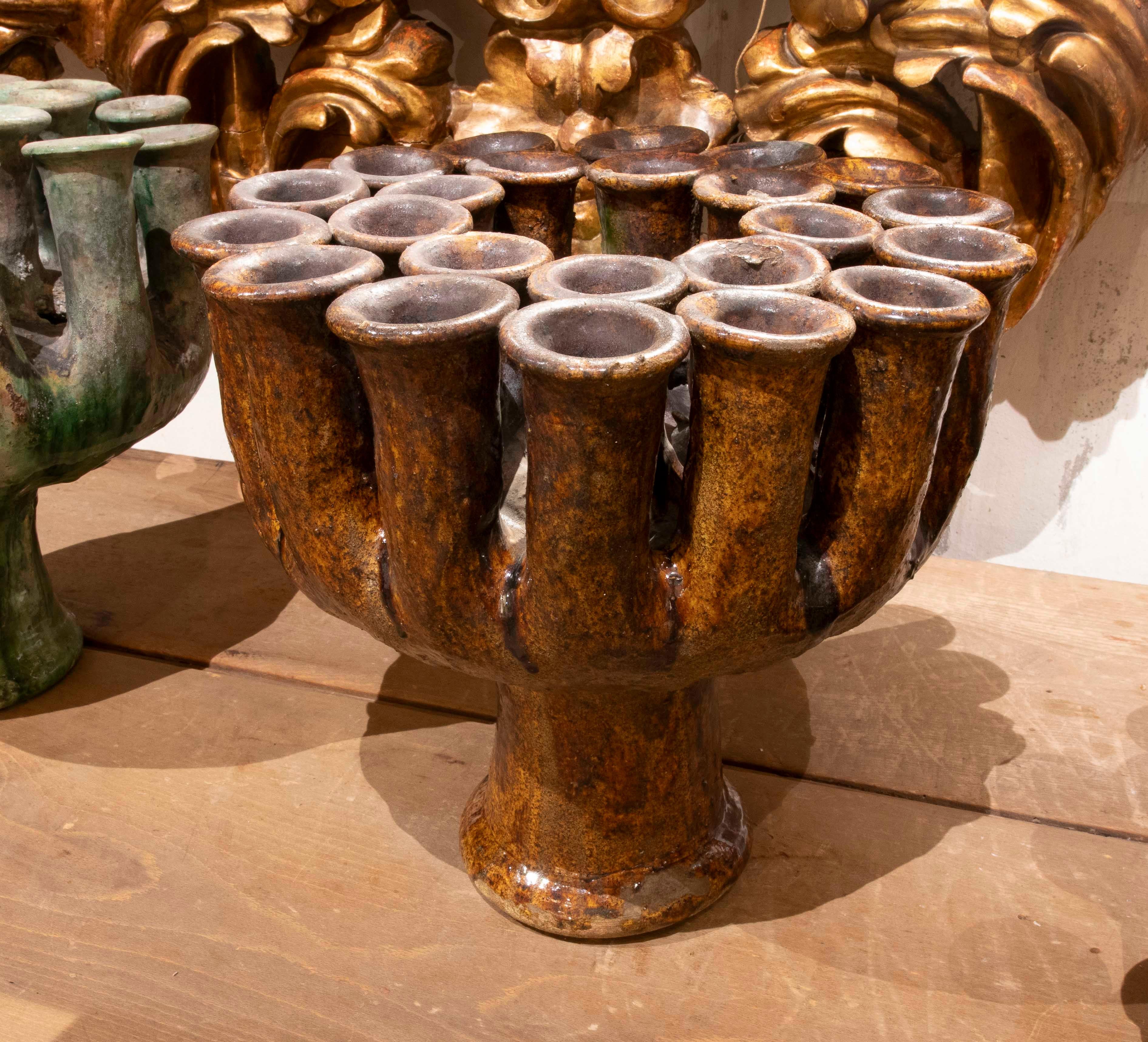 Magnífico candelabro de cerámica tradicional española. Presenta múltiples aberturas y un rico vidriado en tonos miel y ámbar, con una textura brillante y natural que refleja su carácter artesanal. Esta pieza destaca por su forma escultural y sus